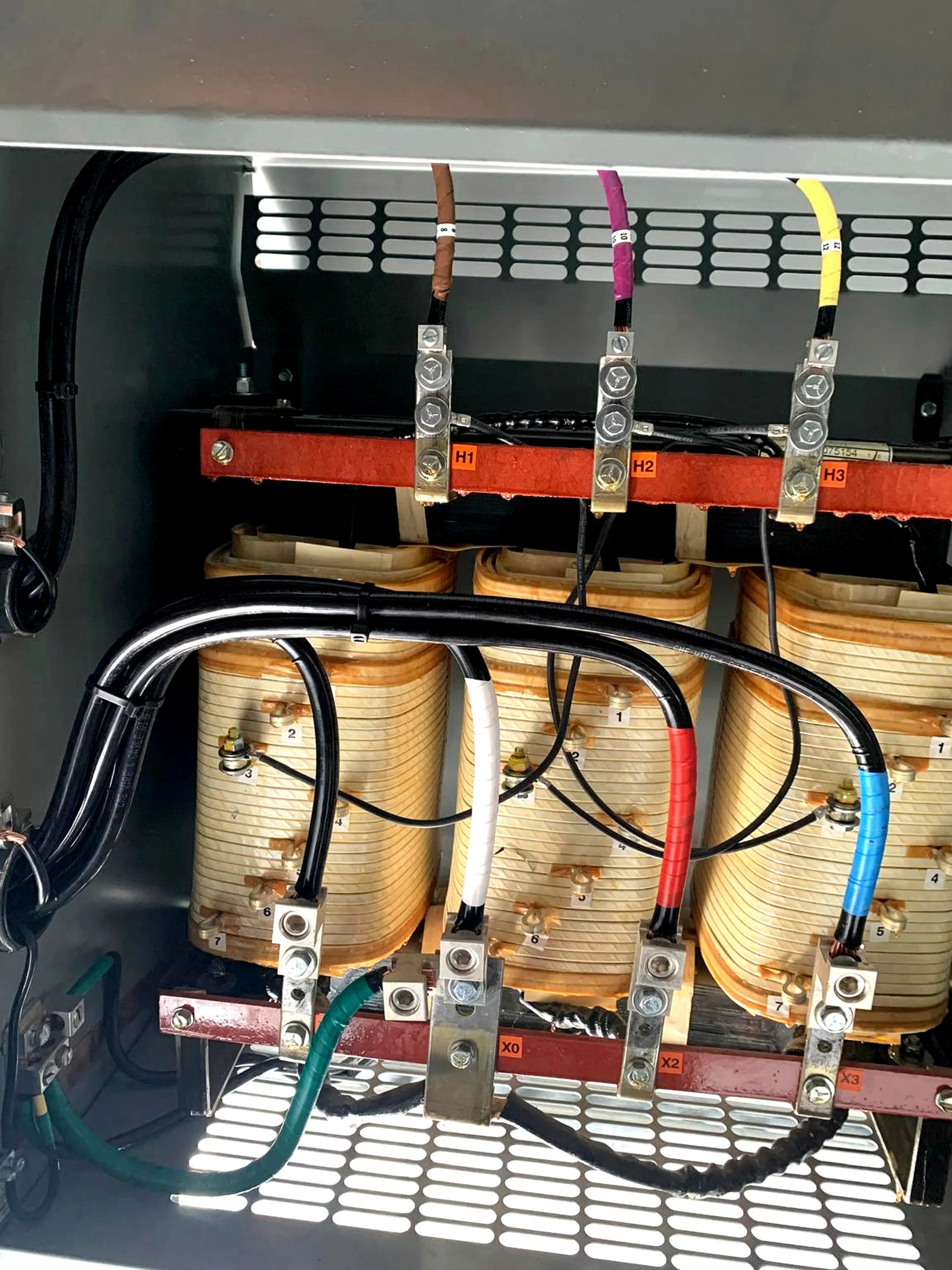 Electrical components inside a control panel with wires connected to a transformer or inductor.