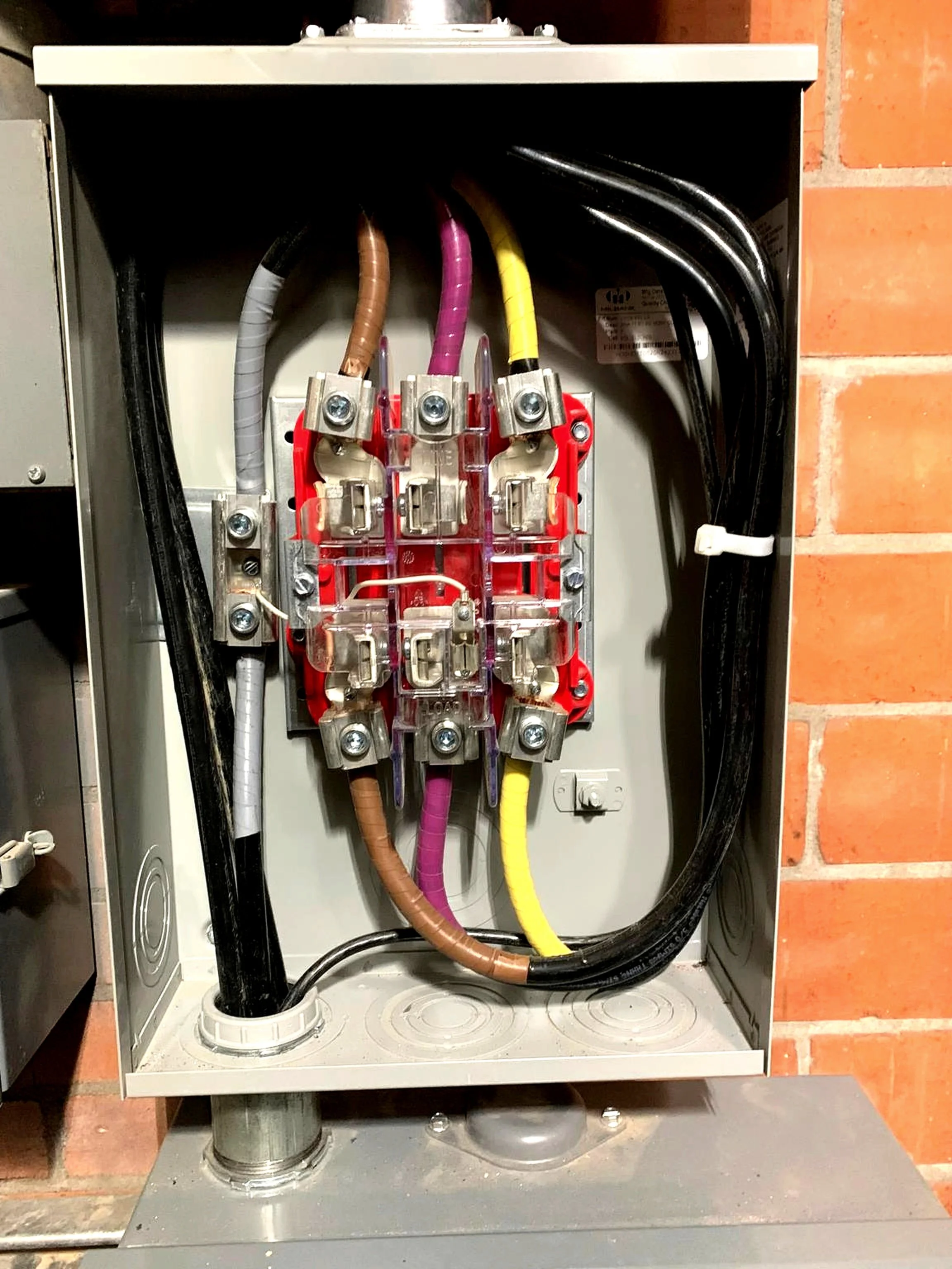 Interior of an electrical panel with multiple colored wires connected to a circuit breaker.