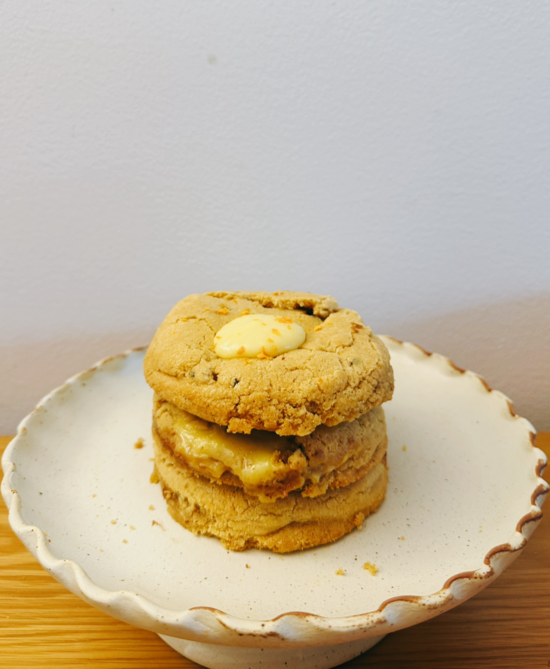 A stack of three cookies on a white scalloped plate, with a white background.