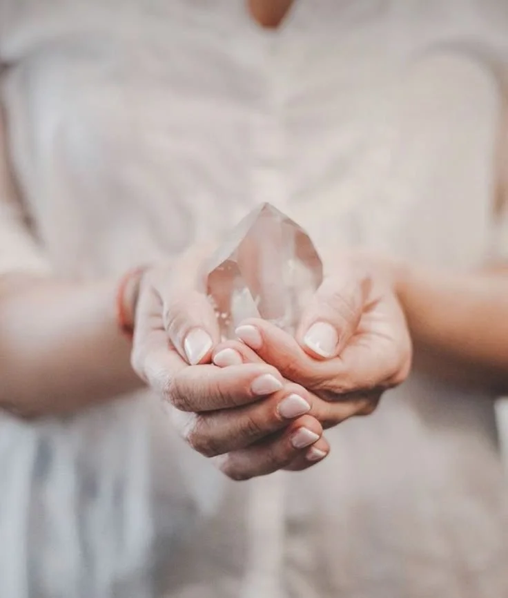 Person holding a clear quartz crystal in both hands.