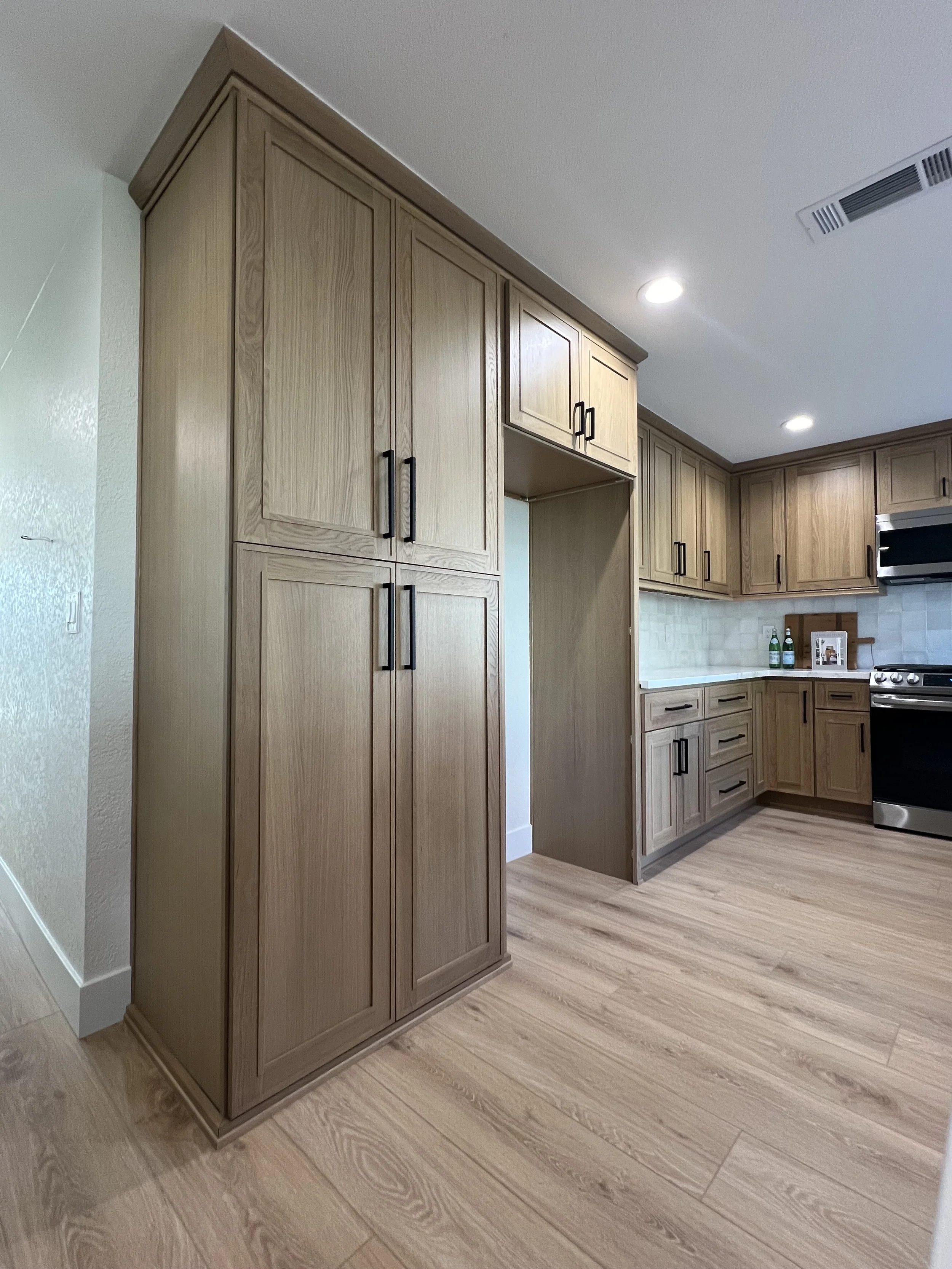 Kitchen with wooden cabinets, a white countertop, a stove, and two bottles of sparkling water on the counter.
