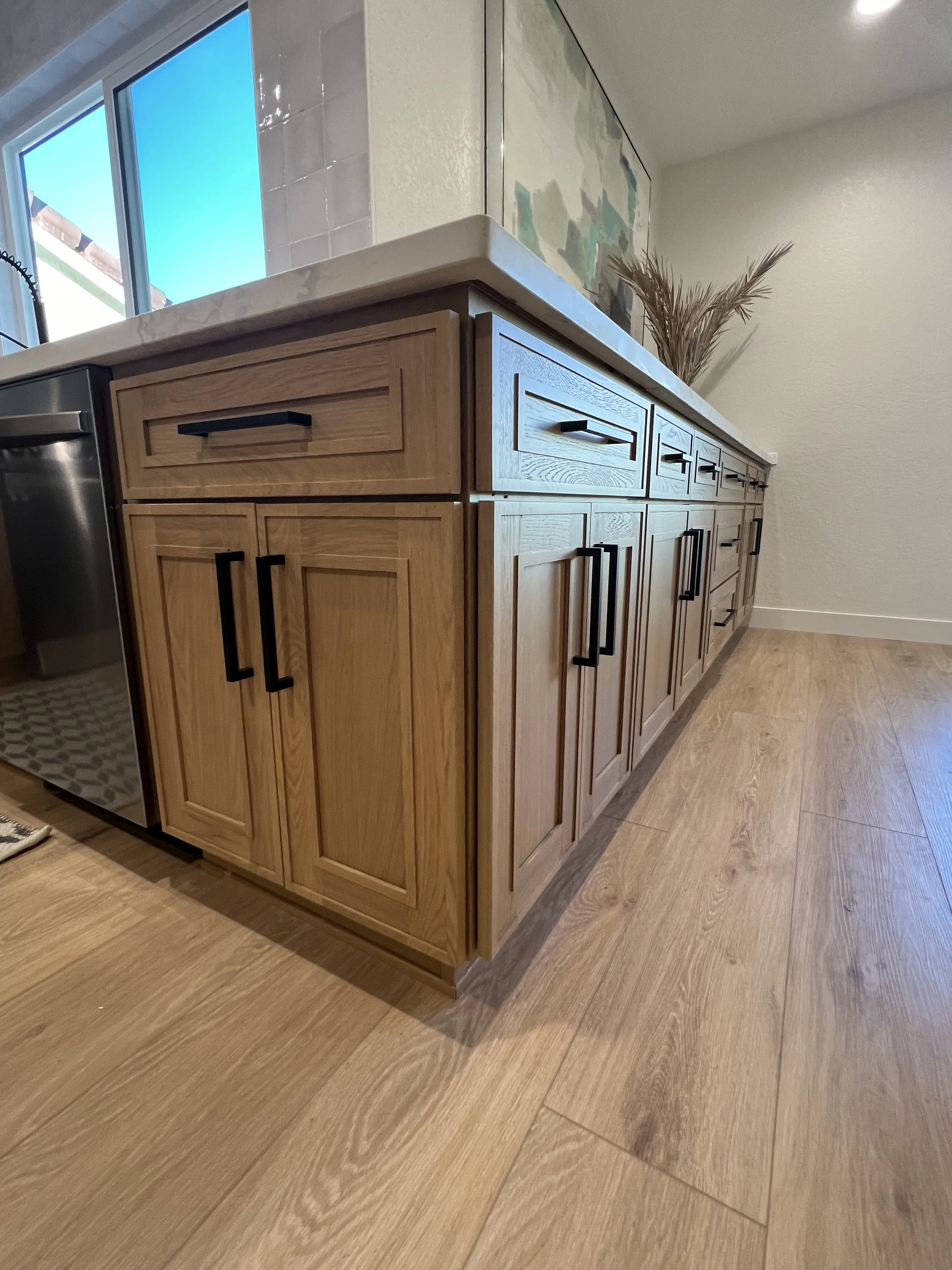 Kitchen with wooden cabinets, a white countertop, and a window showing a blue sky.