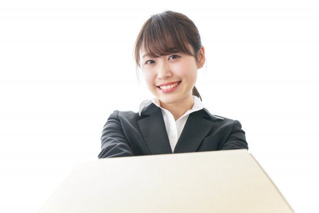 笑顔の女性が白い背景の前で手を差し伸べている