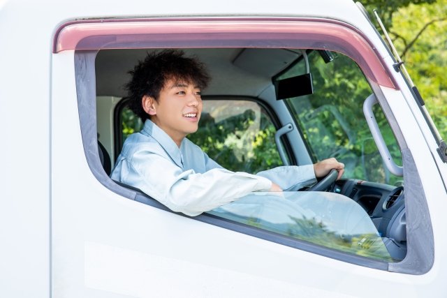 運転手の若い男性がトラックの運転席に座っている