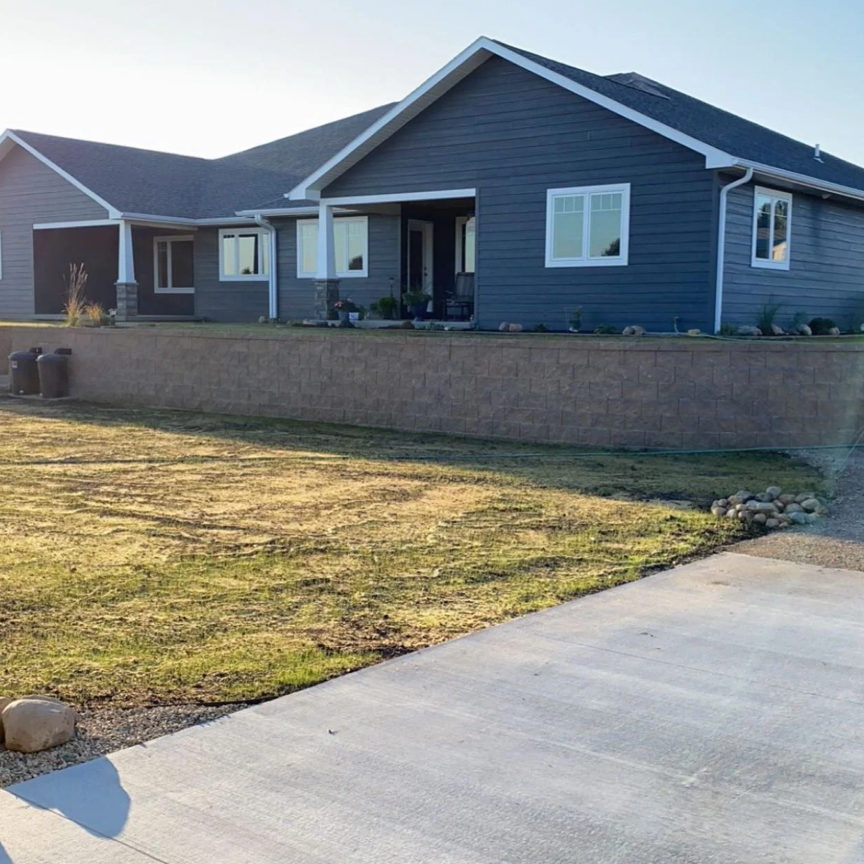 Landscape installation in Watertown, SD featuring a retaining wall and graded lawn area along a residential property. This project improves drainage, adds structure, and enhances overall curb appeal.