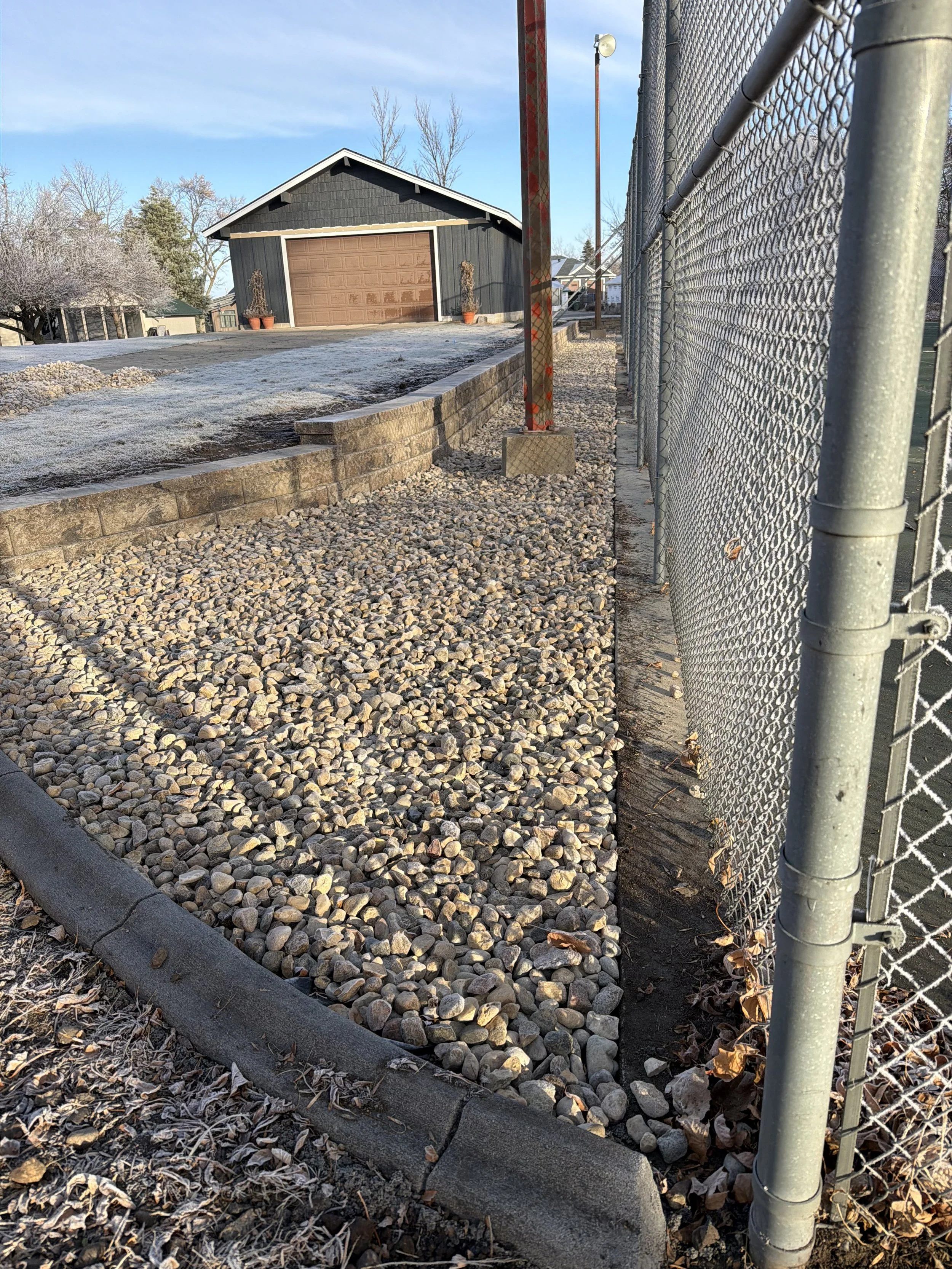 Landscape installation in Watertown, SD featuring decorative rock, clean edging, and a curved landscape border. This project provides a low-maintenance solution while improving drainage and overall curb appeal.