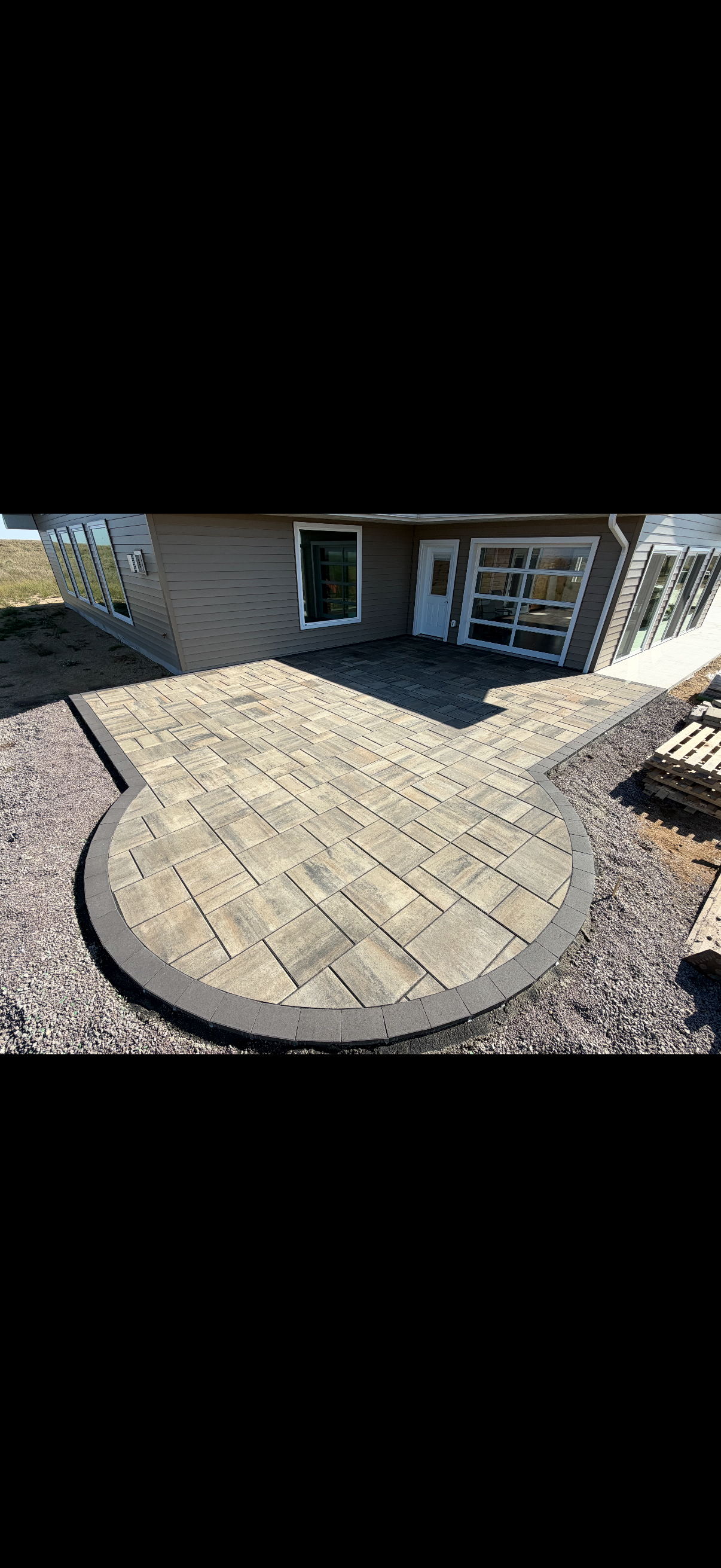 Custom paver patio installation in Watertown, SD featuring a modern design with curved edges, providing a functional and stylish outdoor living space.