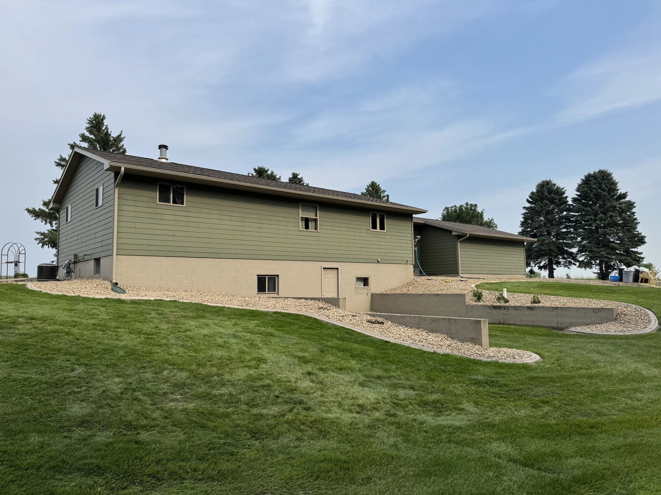 Residential landscape renovation in Watertown, SD with rock installation, grading, and drainage improvements for a low-maintenance and polished look.