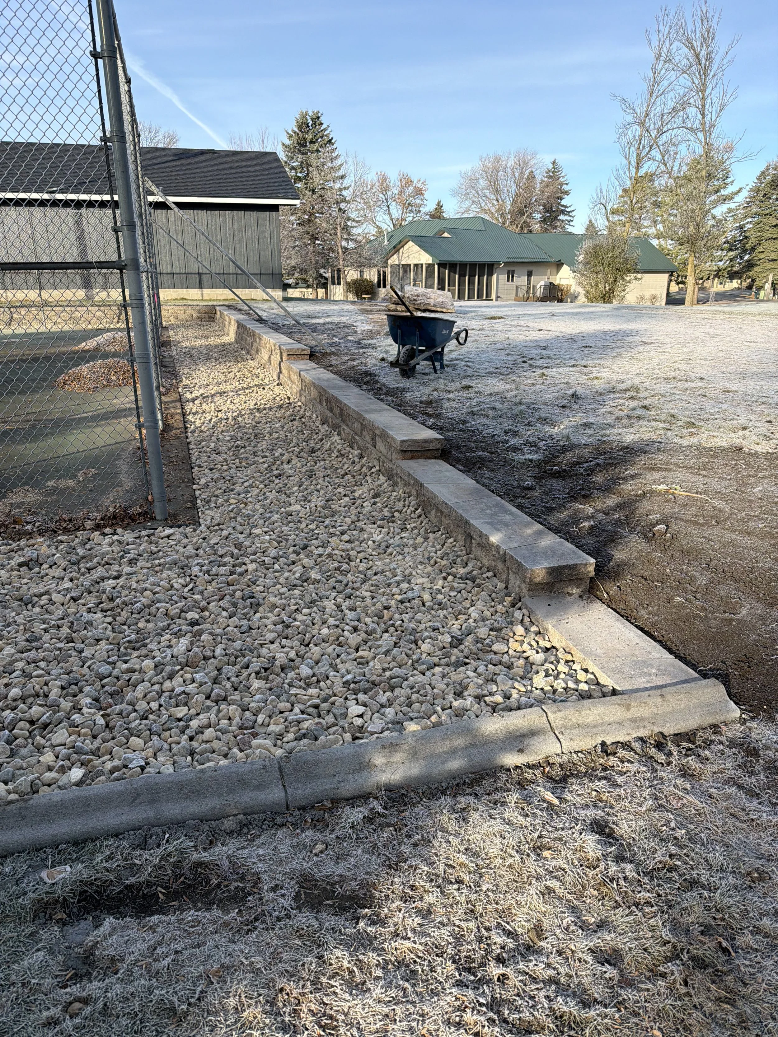 Landscape renovation in Watertown, SD with decorative rock, retaining wall, and defined edging along the property line. This project improves structure, drainage, and long-term durability.
