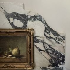 Abstract black and white marble wall with a framed still life painting partly visible in the lower left corner.