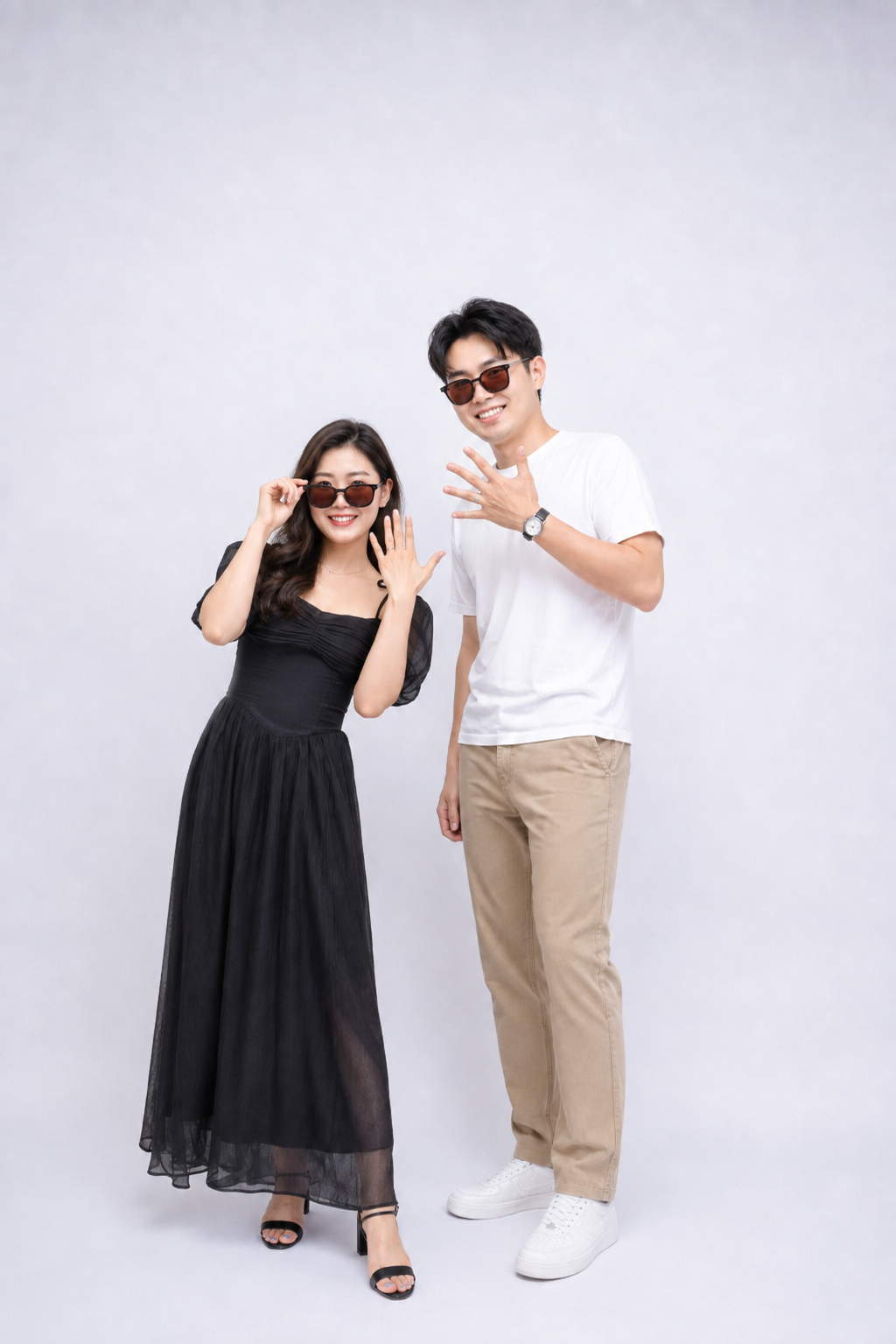 A young woman and man standing together, both wearing sunglasses and smiling.