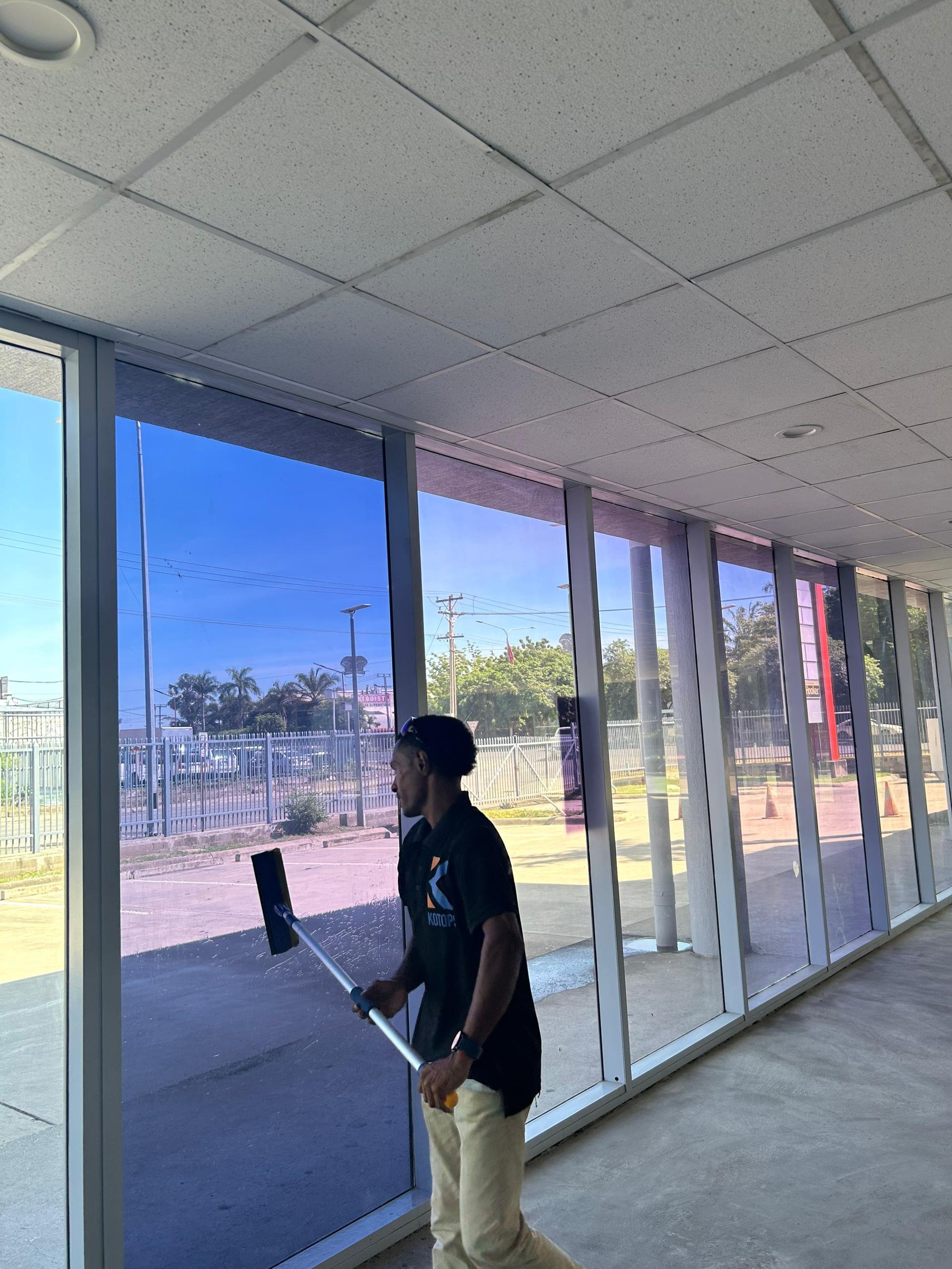 Man cleaning large glass windows inside a commercial building during daytime.