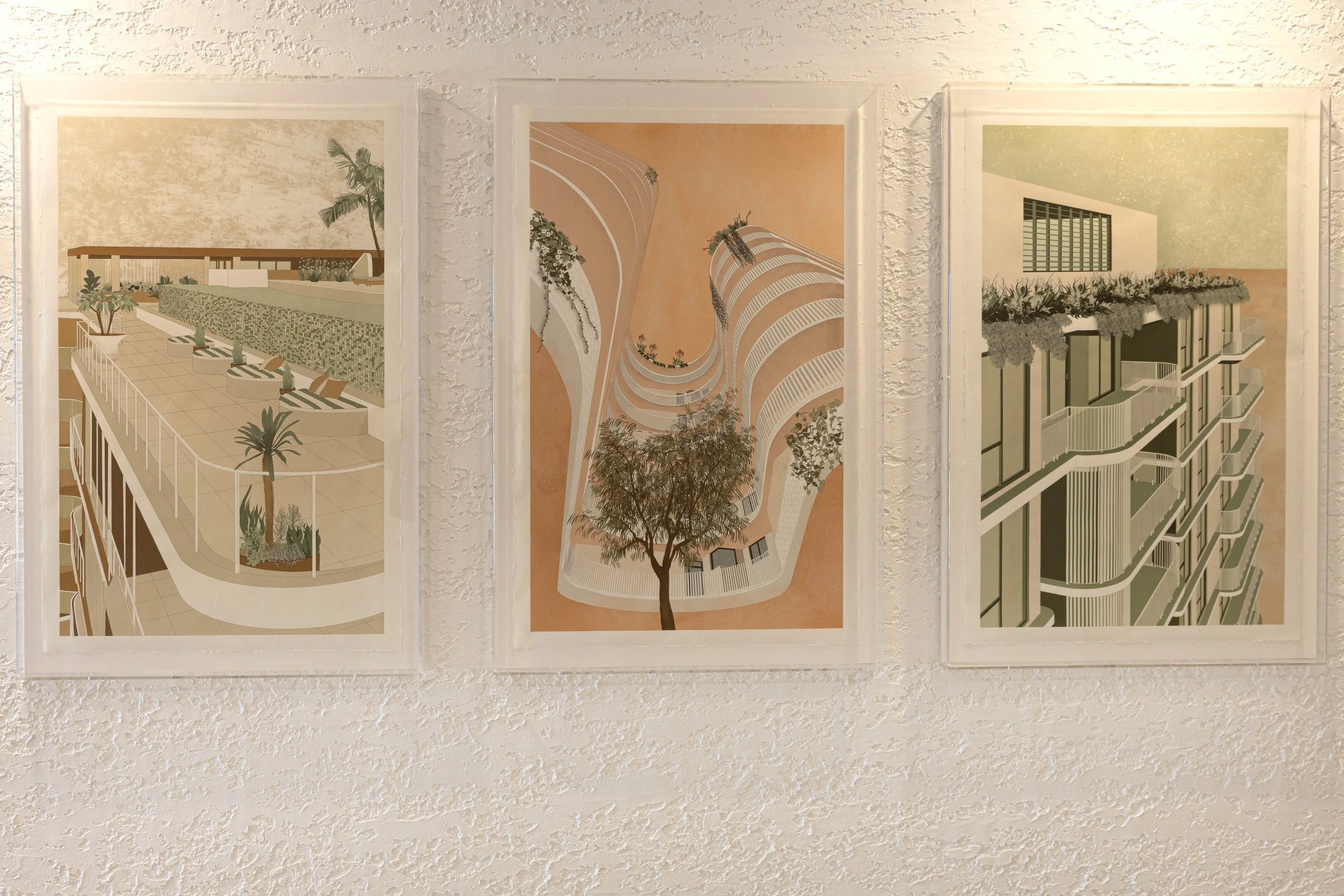 Three framed architectural illustrations of modern buildings and urban design, mounted on a textured white wall.
