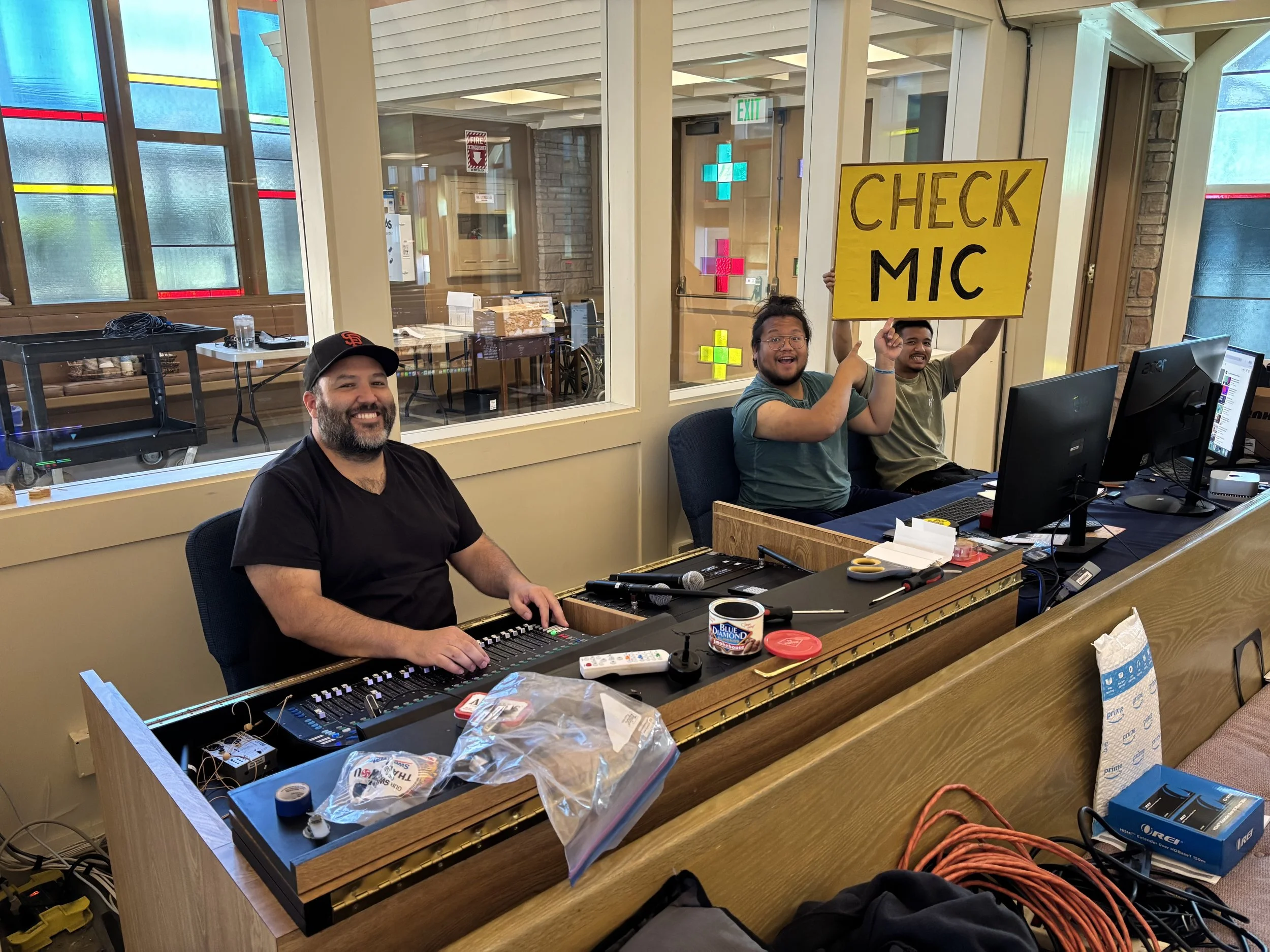 Men adjusting sound and holding "check mic" sign during Sunday worship service for technical and A/V  support