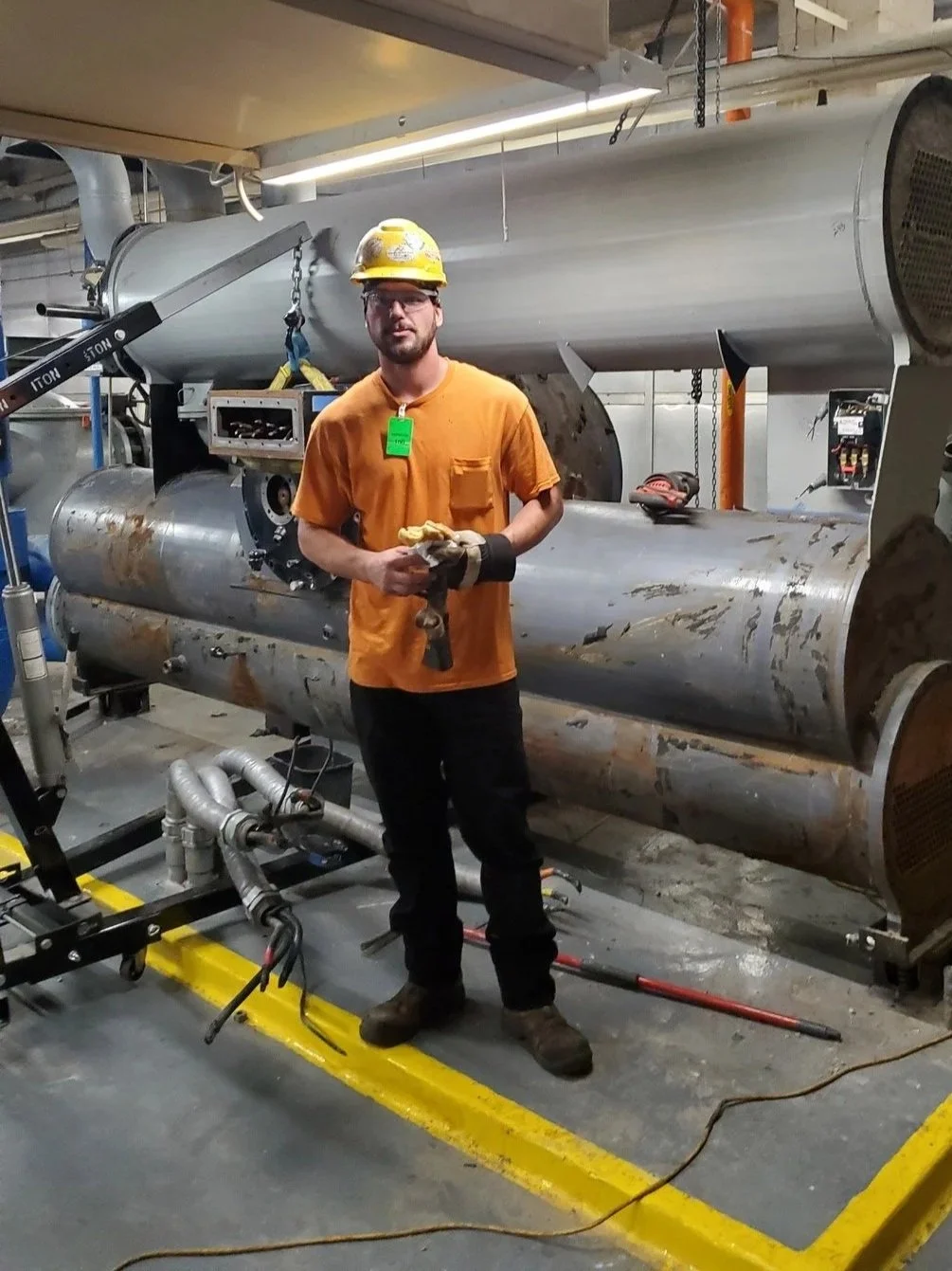 Professional at work, Owner of Boiler Chiller Killers, Gadge Bell, standing in front of a massive chiller system that they are about to remove on this commercial job