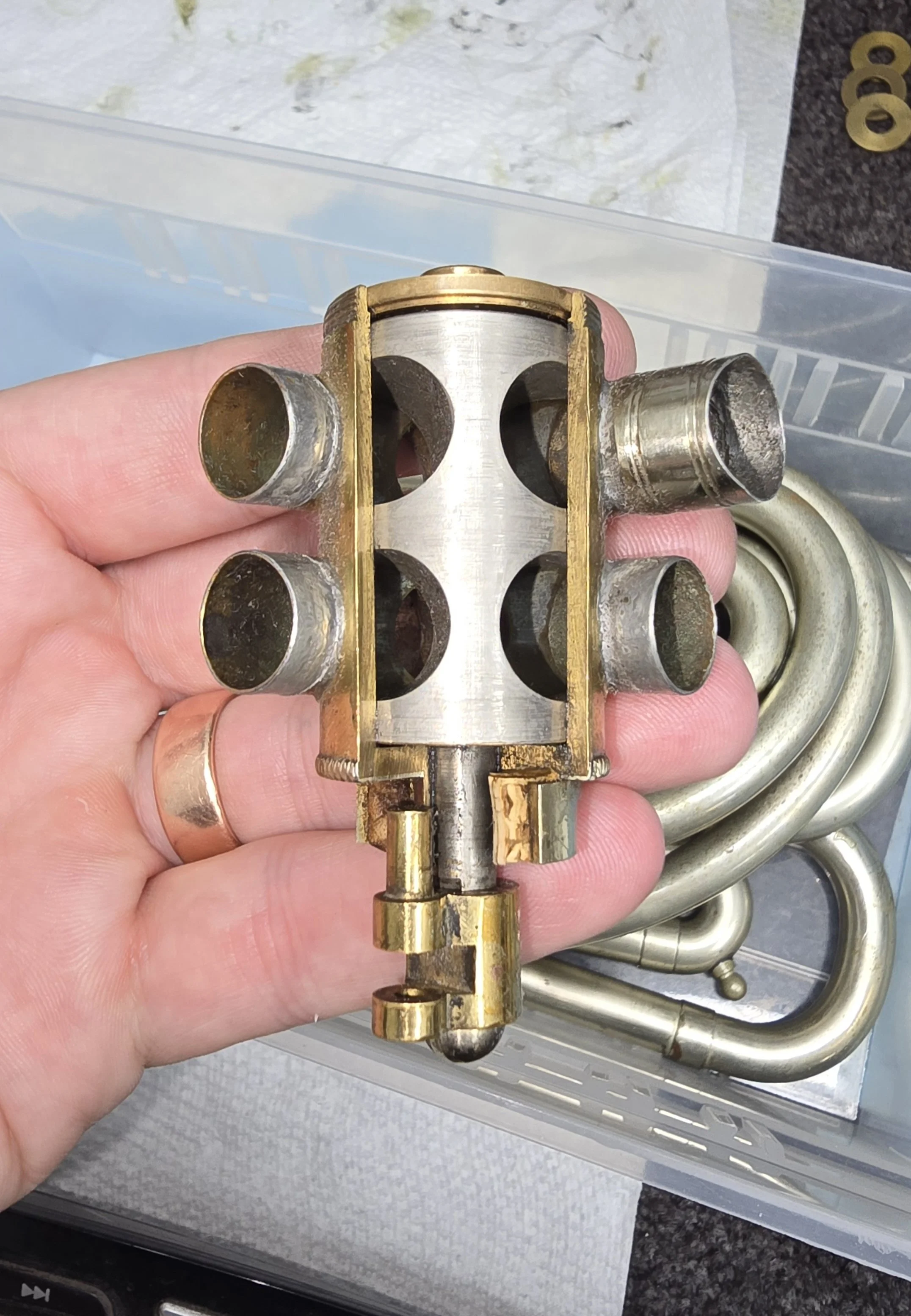 A cutaway view of a double french horn rotor valve with a nickel plated rotor visible along with the bearing and stop arm.