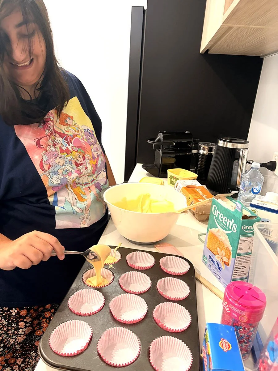 Woman filling cupcake liners with batter in a kitchen