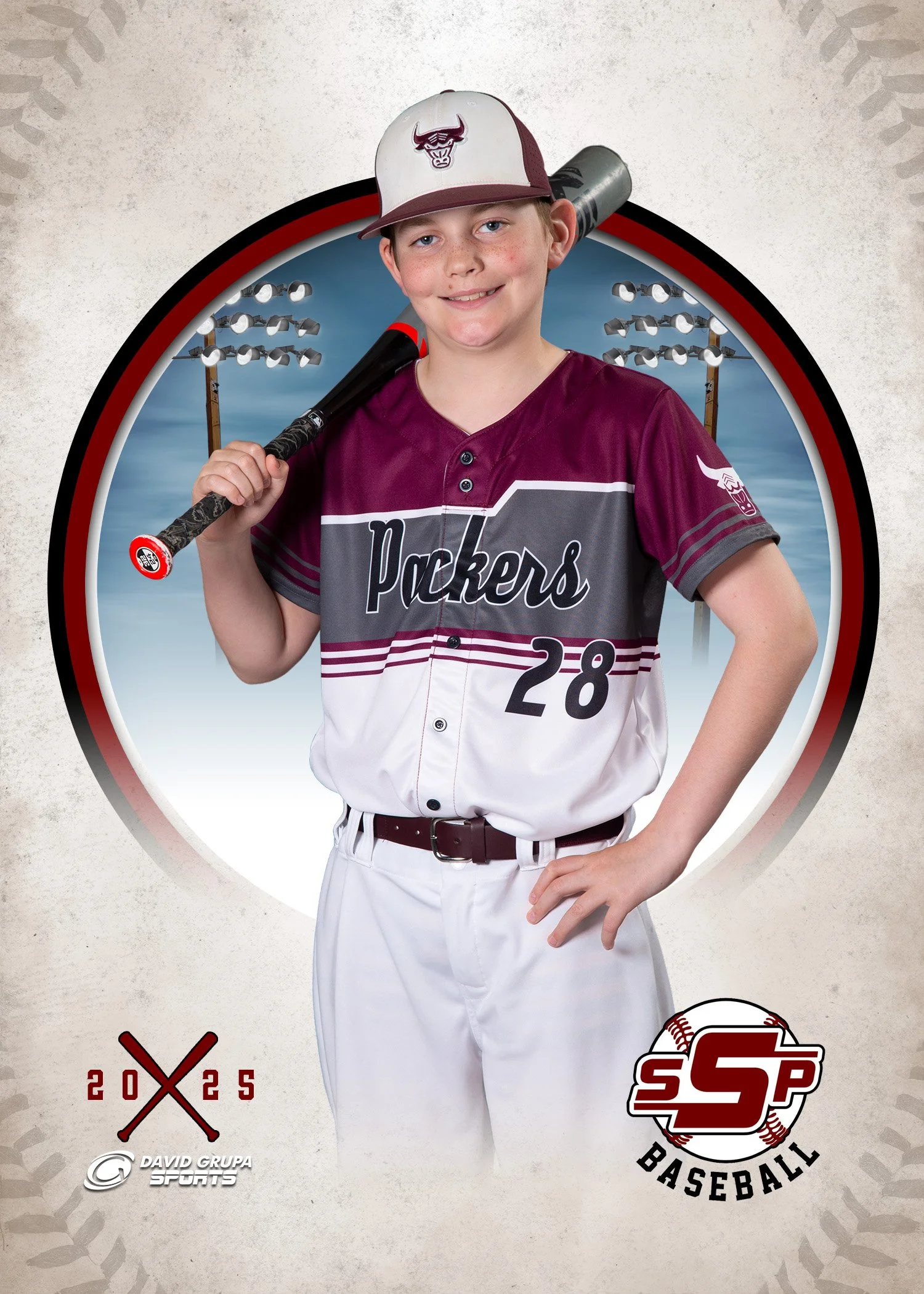A young boy in baseball uniform holding a bat over his shoulder with a stadium background.