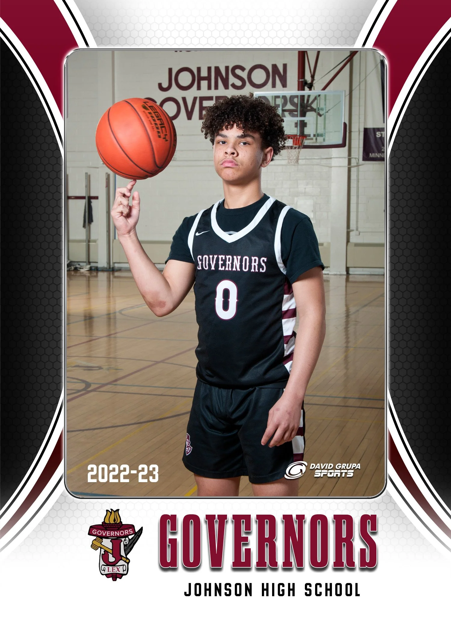 A young male basketball player in a Johnson High School Governos team uniform standing in a gymnasium, spinning a basketball on his finger.