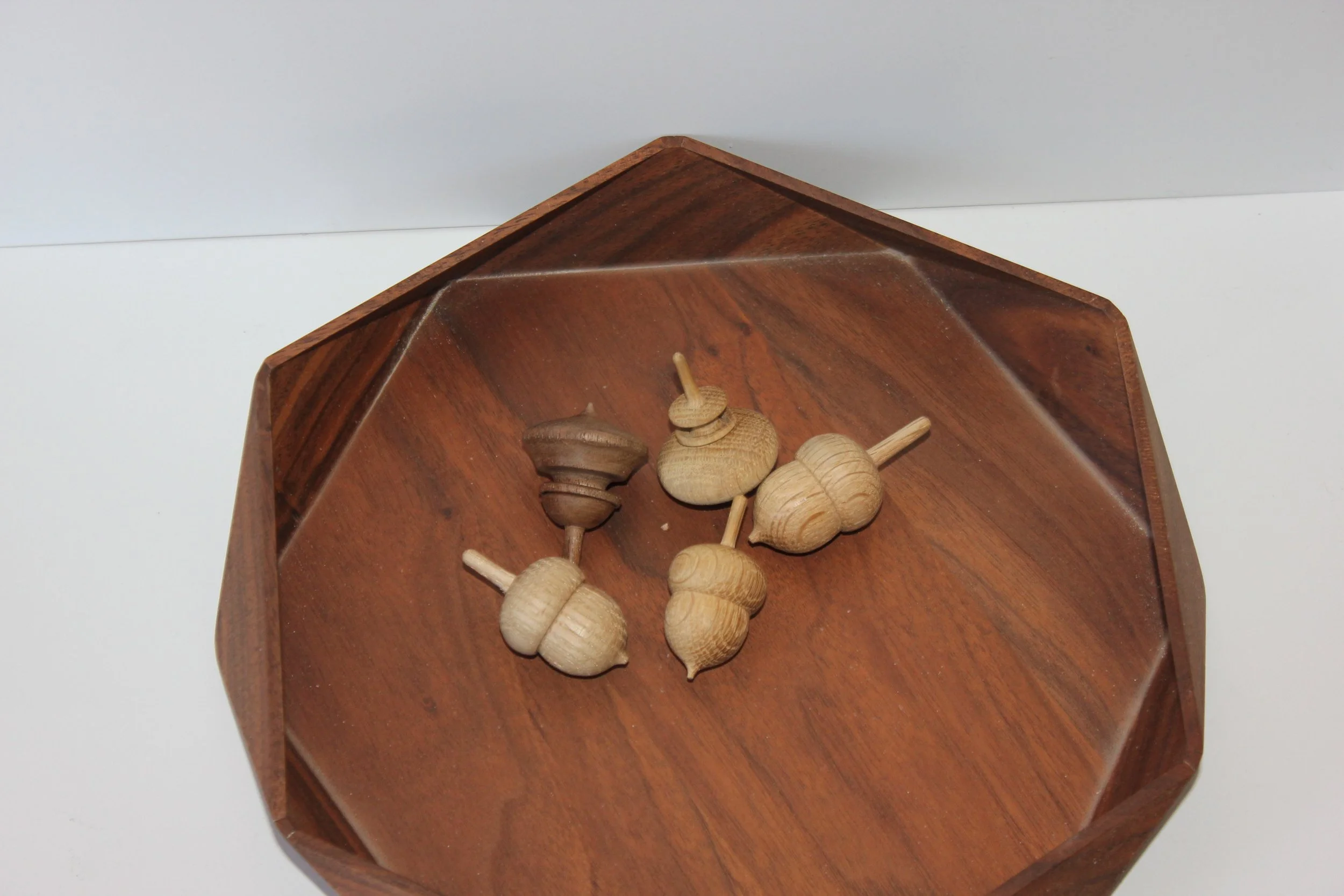 A wooden hexagonal box containing small wooden spinning tops.