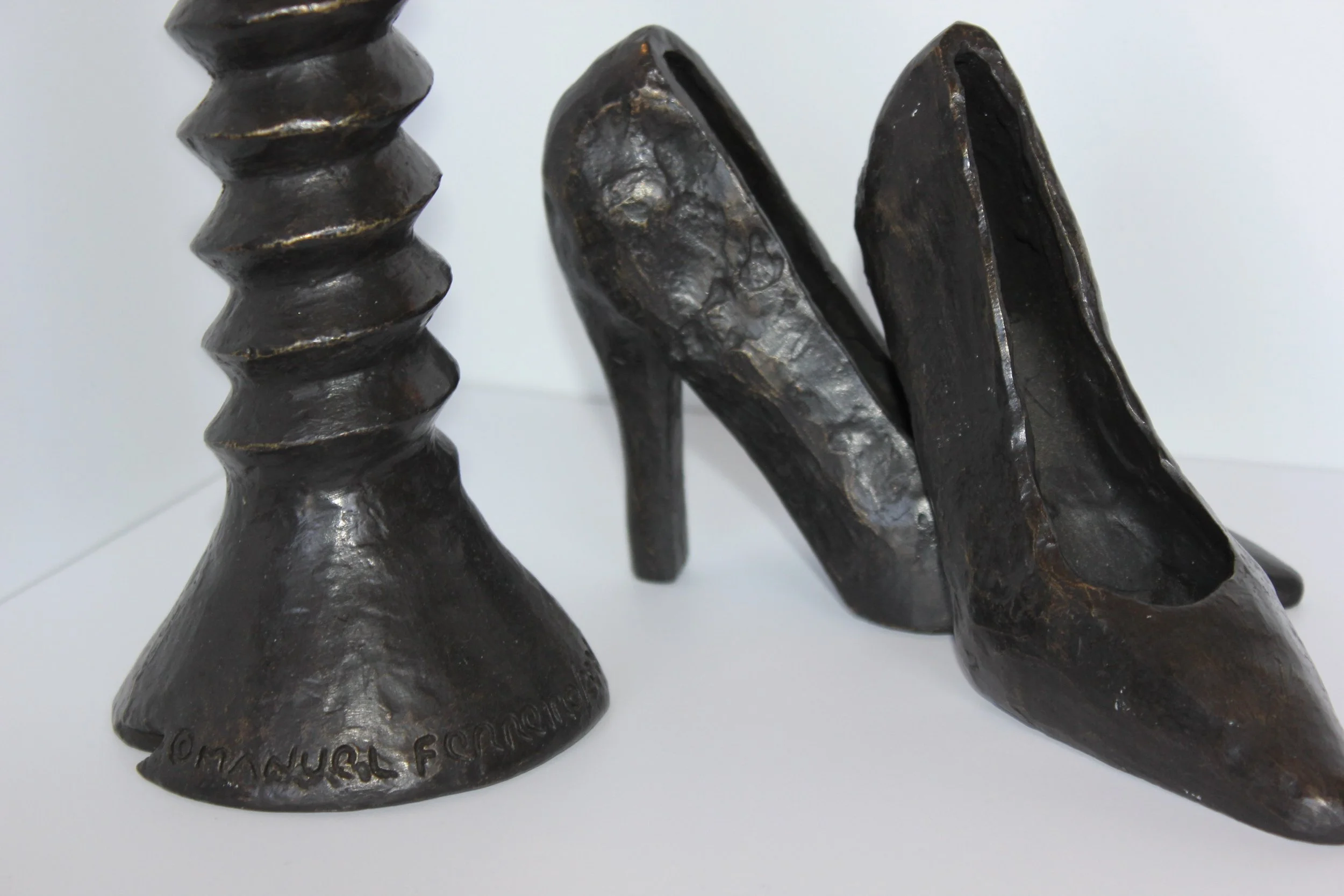 Close-up of three dark metallic bookends with textured surfaces and irregular shapes, positioned on a white surface.