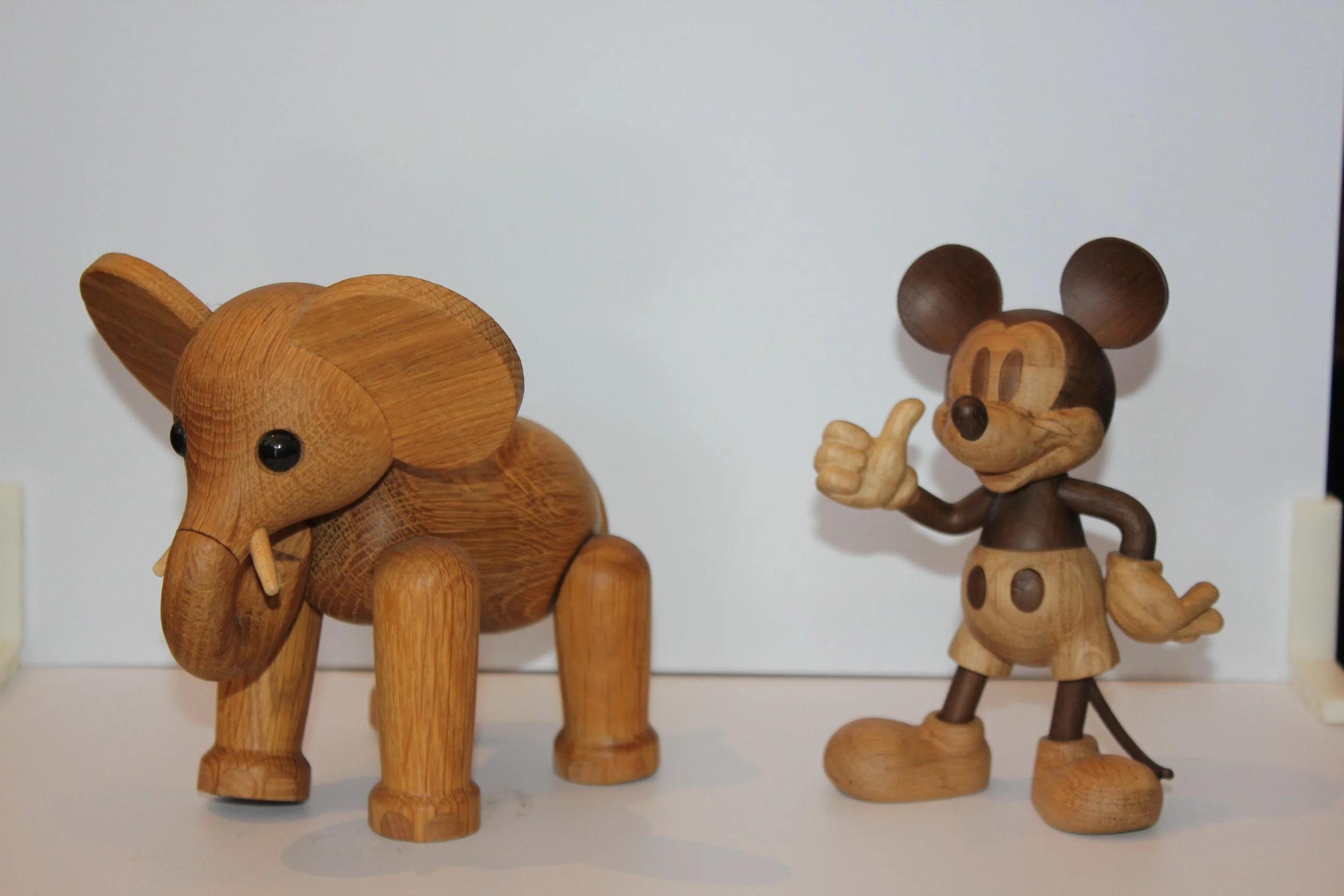 Wooden animal figurines of an elephant and a mouse, with the mouse giving a thumbs-up.