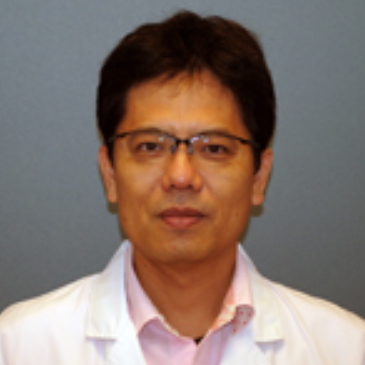 A middle-aged Asian male doctor wearing glasses, a white lab coat, and a pink dress shirt, standing against a gray background.