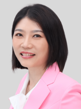 Portrait of a woman with short black hair wearing a pink blazer and white top, smiling against a light gray background.