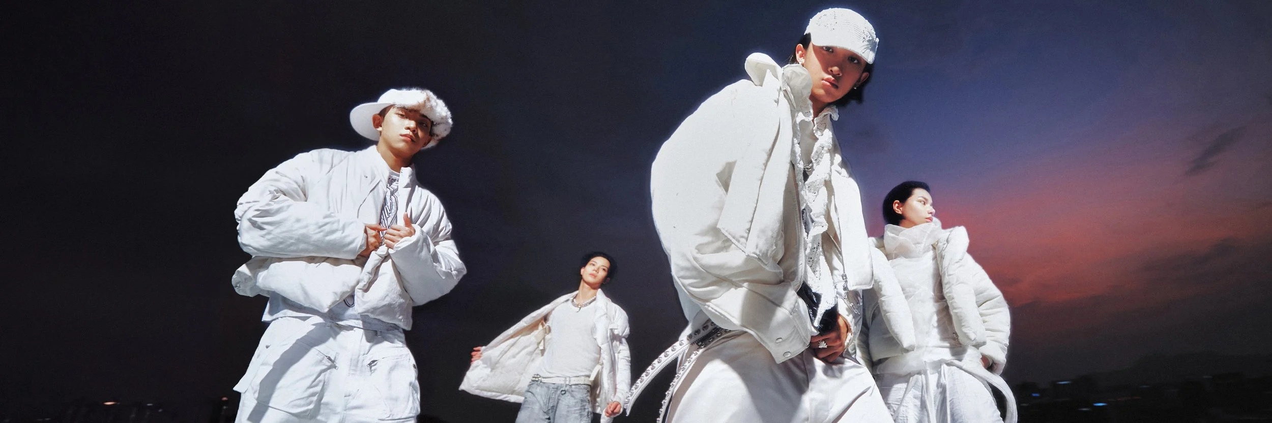 A group of five people dressed in white clothing and accessories, standing outdoors during sunset.
