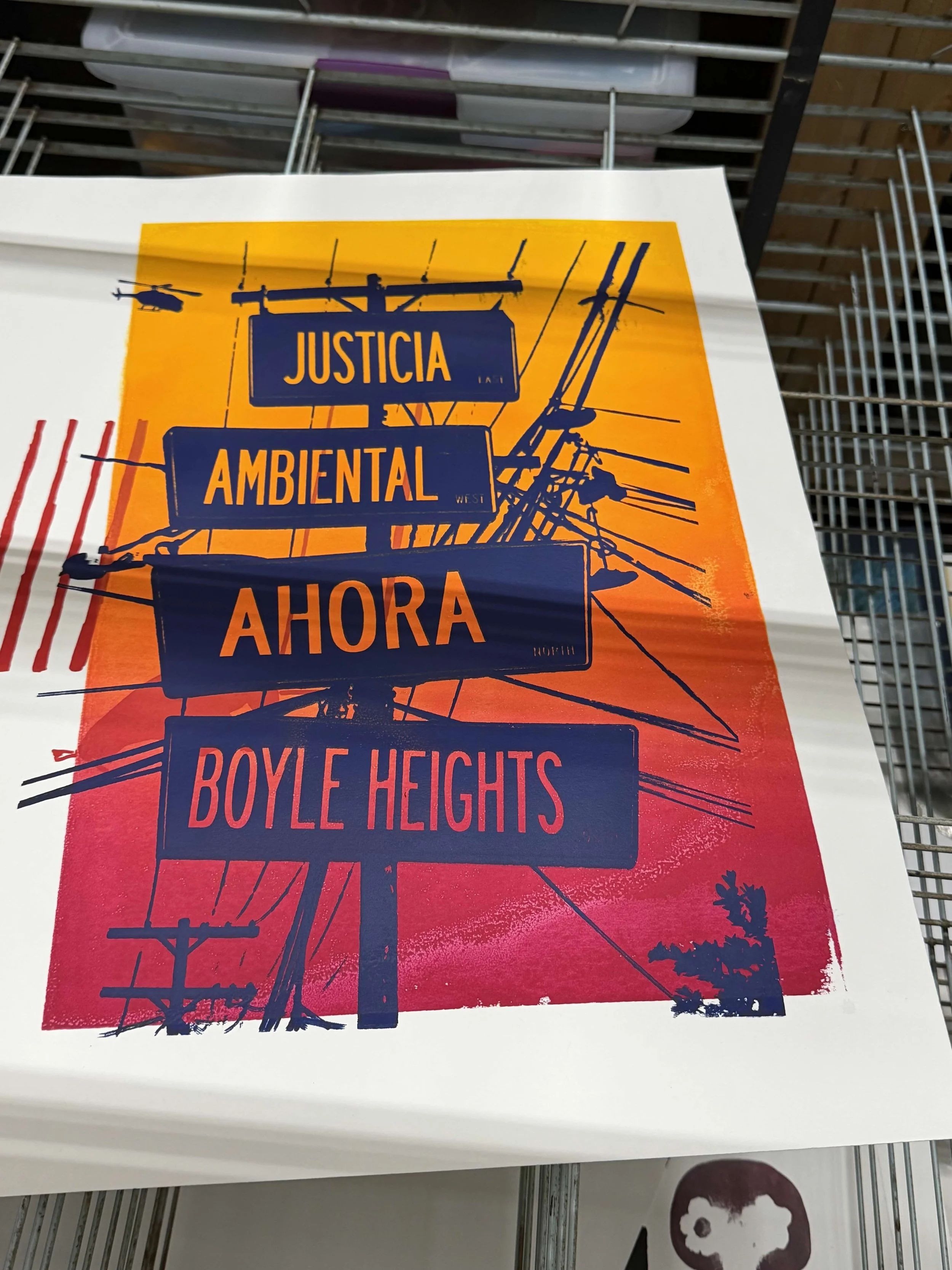 Poster with a depiction of power lines and palm trees, with text in Spanish that reads 'JUSTICIA AMBIENTAL AHORA' and 'BOYLE HEIGHTS'.