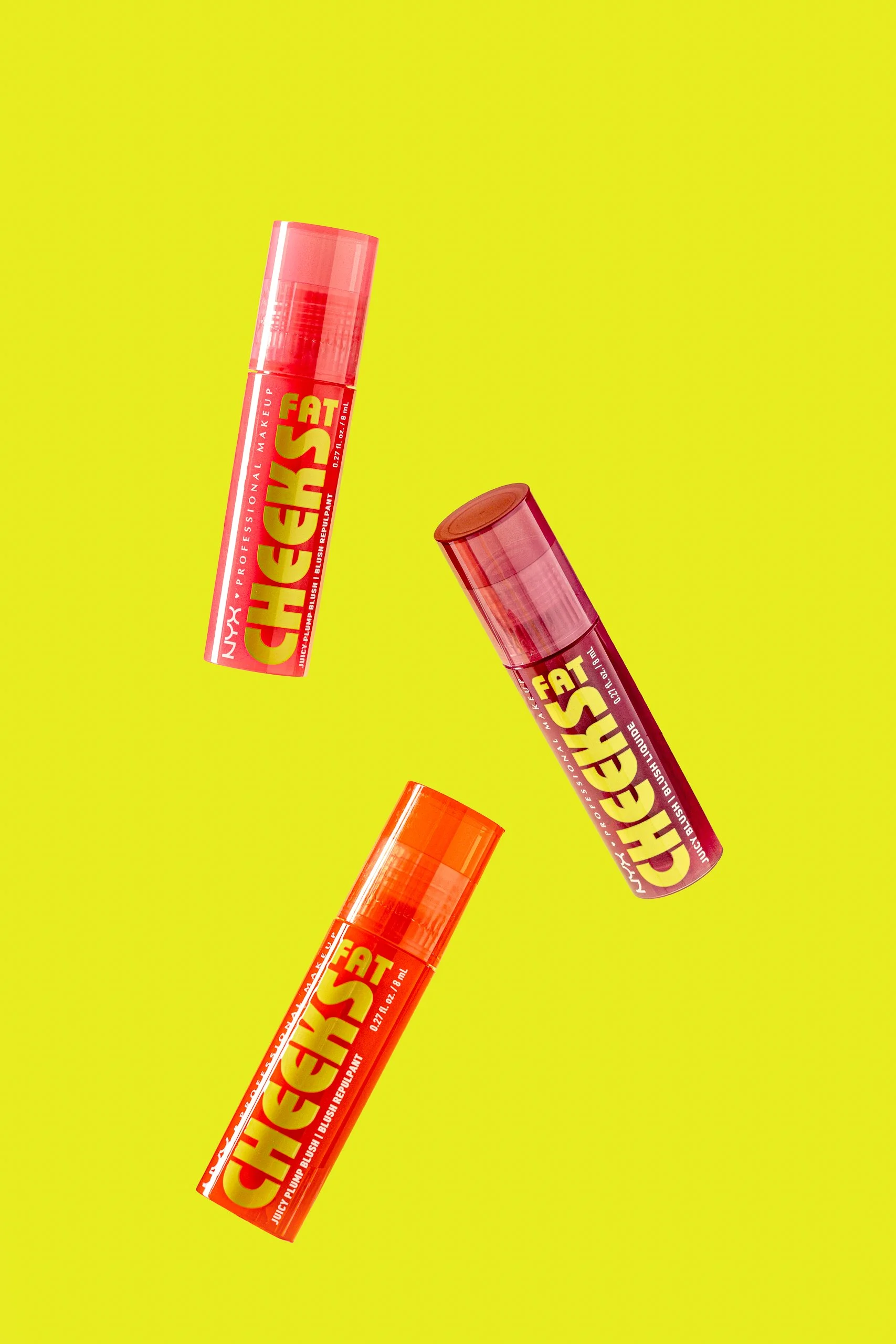 Three lip balm tubes with bright orange caps and red labels, floating against a yellow background.