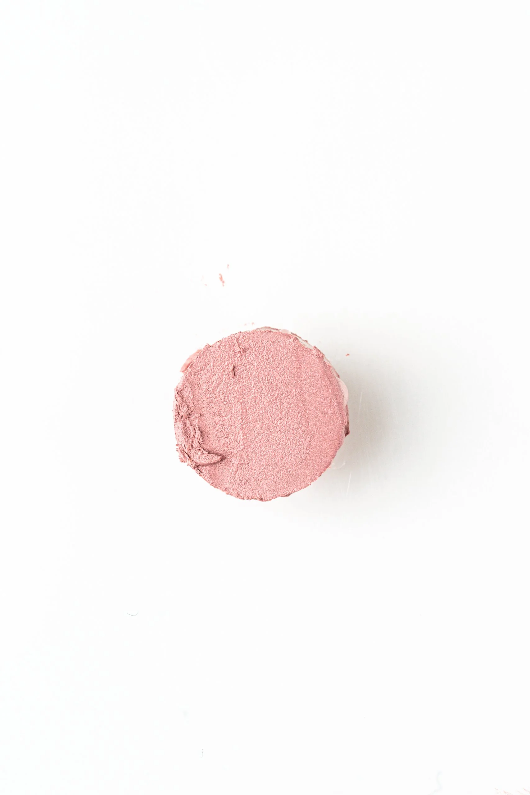 A slice of pink lipstick on a white surface.