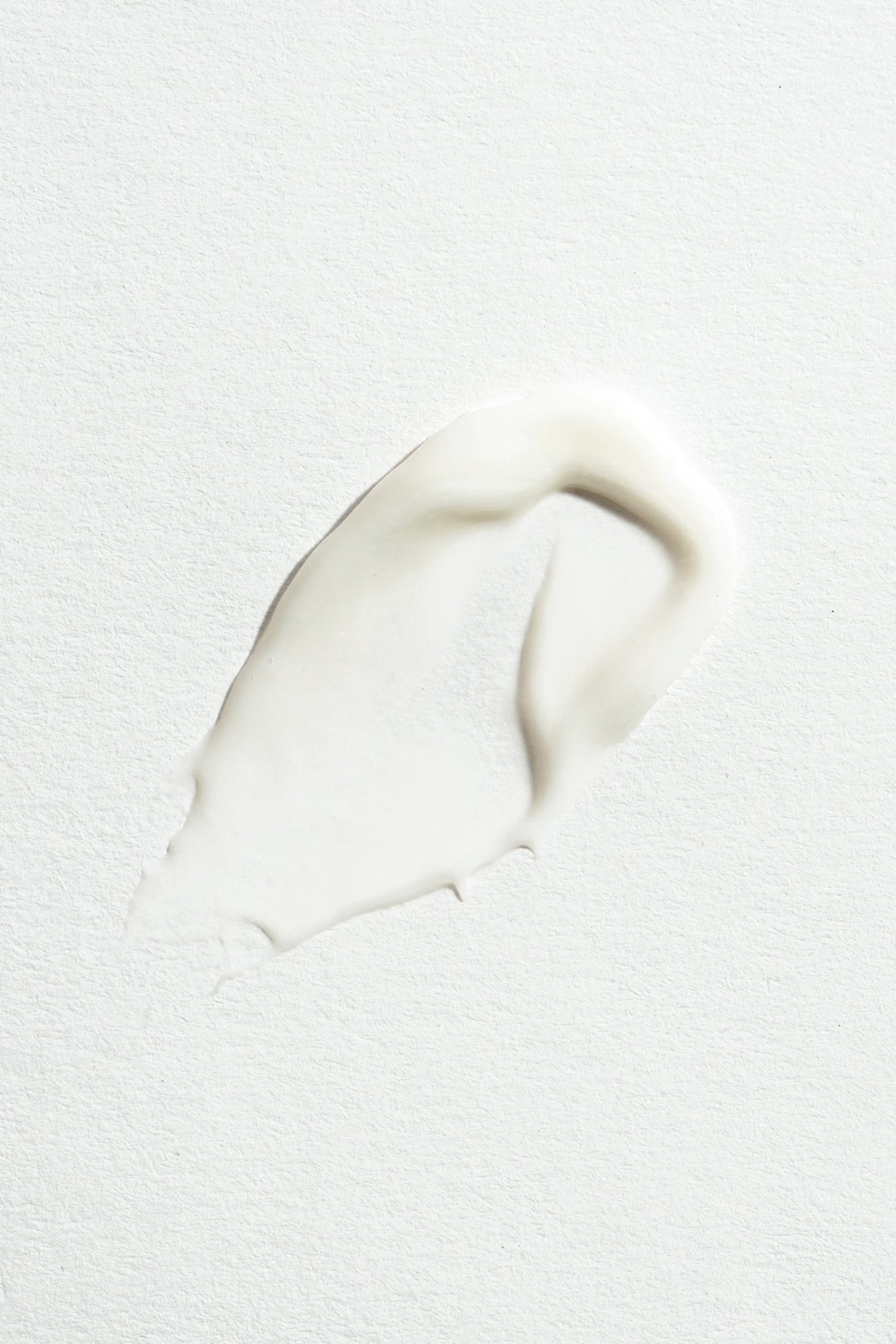 A streak of white creamy substance spread on a textured white surface.