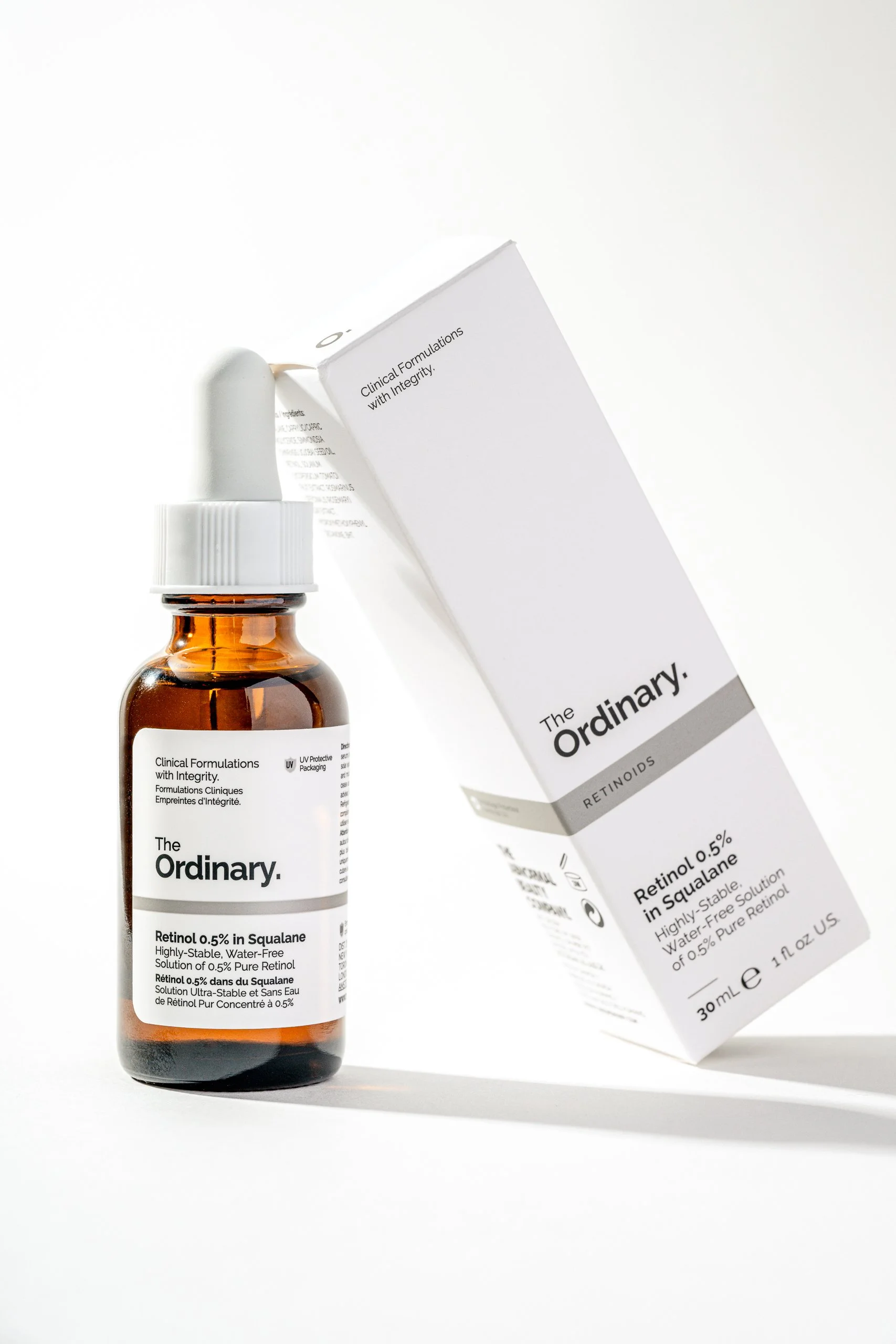 A small amber glass bottle with a white cap and dropper, labeled 'The Ordinary Retinol 0.5% in Squalane', and a white box with similar text and product information, set against a white background.
