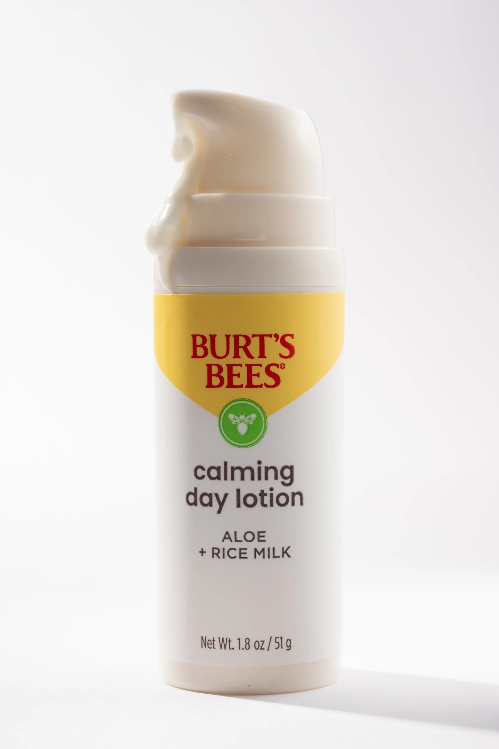 Bottle of Burt's Bees calming day lotion with aloe and rice milk, featuring a partially squeezed tube with white lotion and a yellow cap with red text.