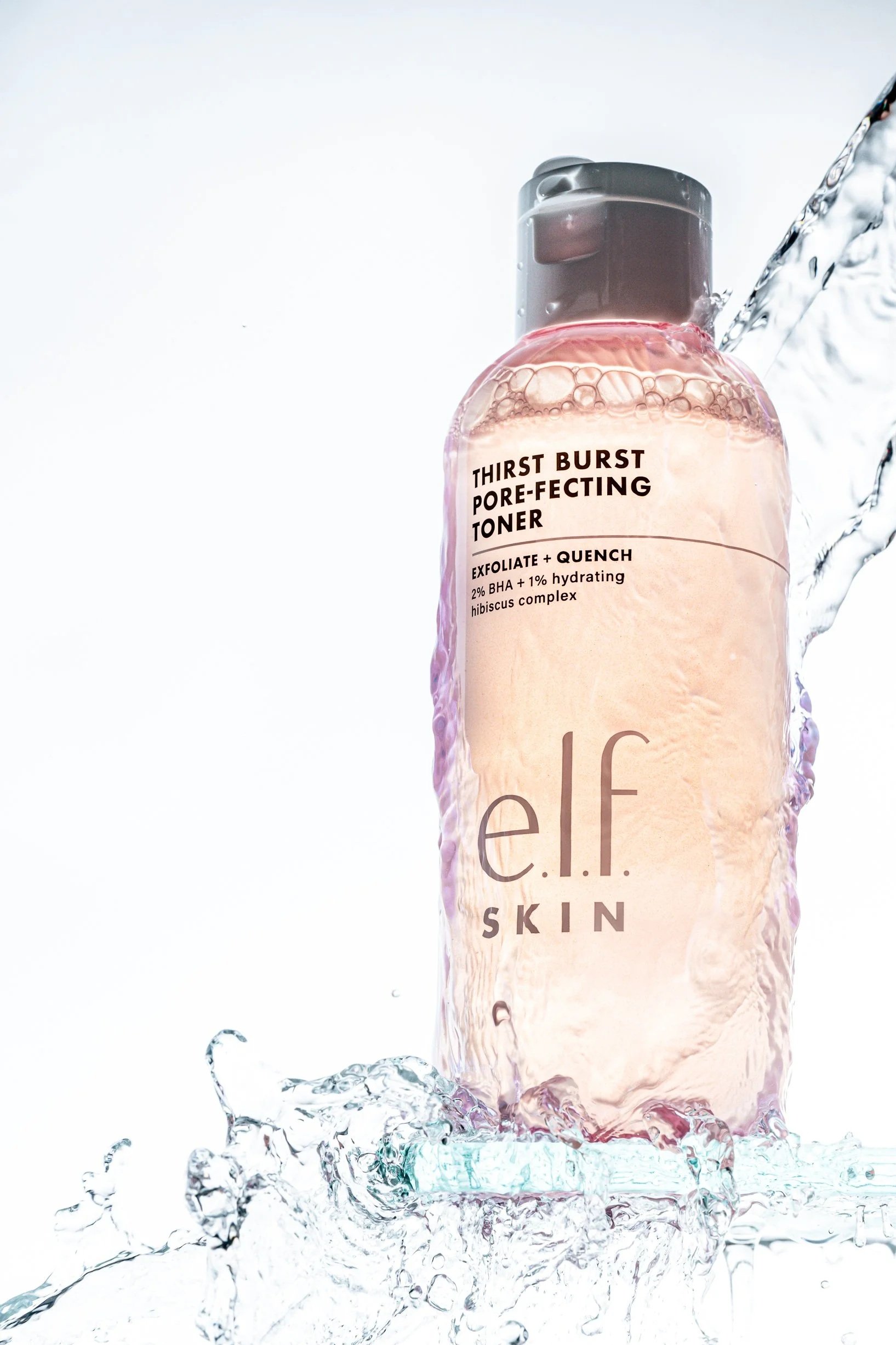 A skincare product bottle labeled 'Thirst Burst Pore-Perfecting Toner' with splash of water around it, against a white background.