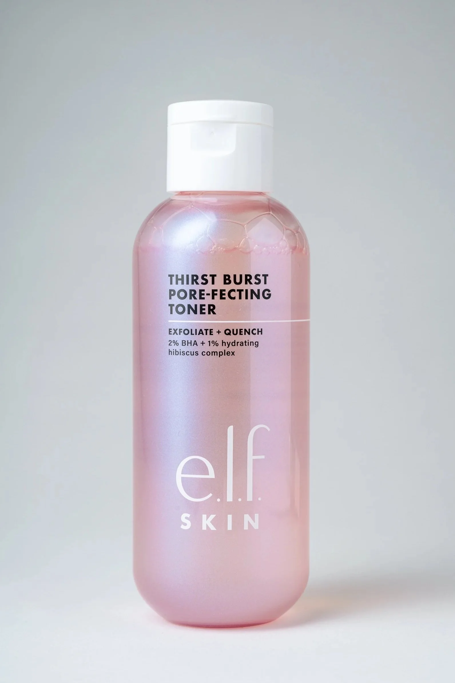 A pink bottle of e.l.f. skincare toner with a white cap, featuring the label 'Thirst Burst Pore-Perfecting Toner' with ingredients like 2% BHA and 1% hydrating hibiscus complex.