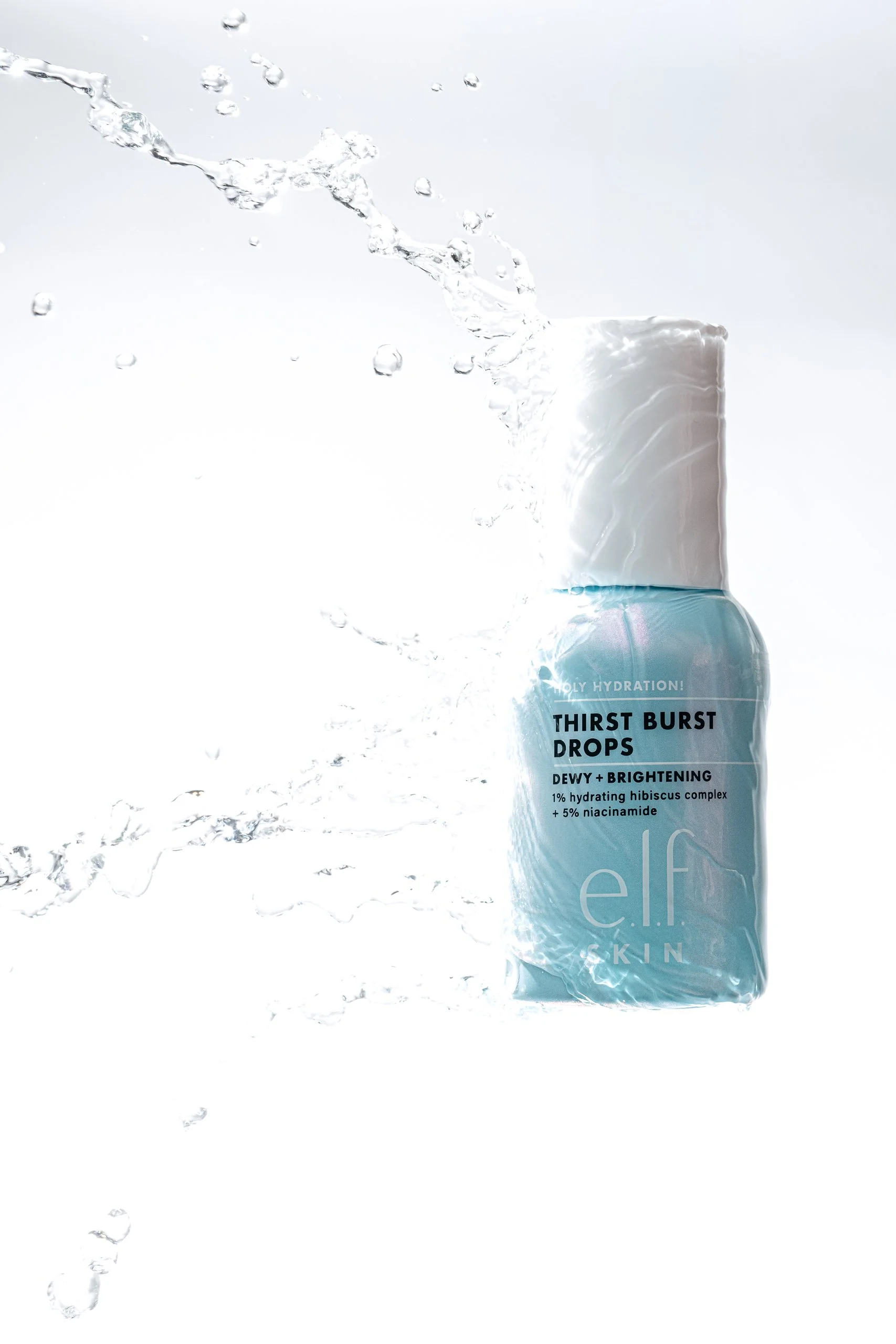 A bottle of elf SKIN Thirst Burst Drops with water splashing around it.