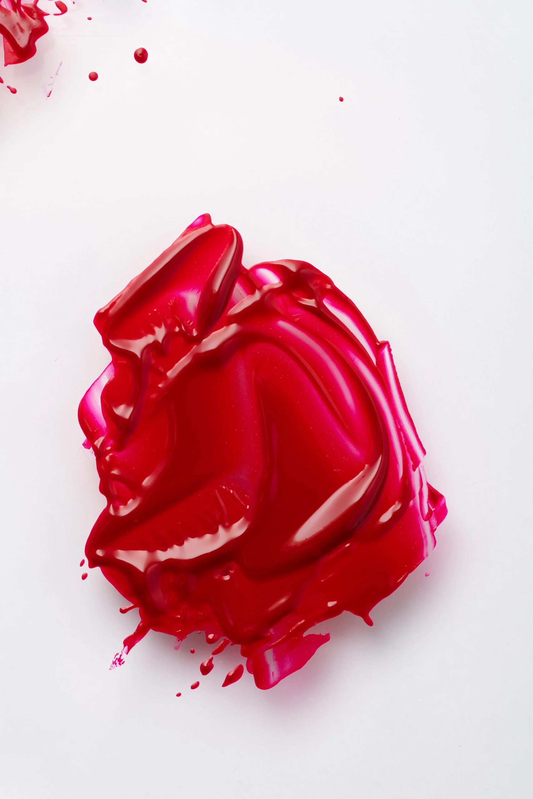Red lipstick splattered and spread over white background.