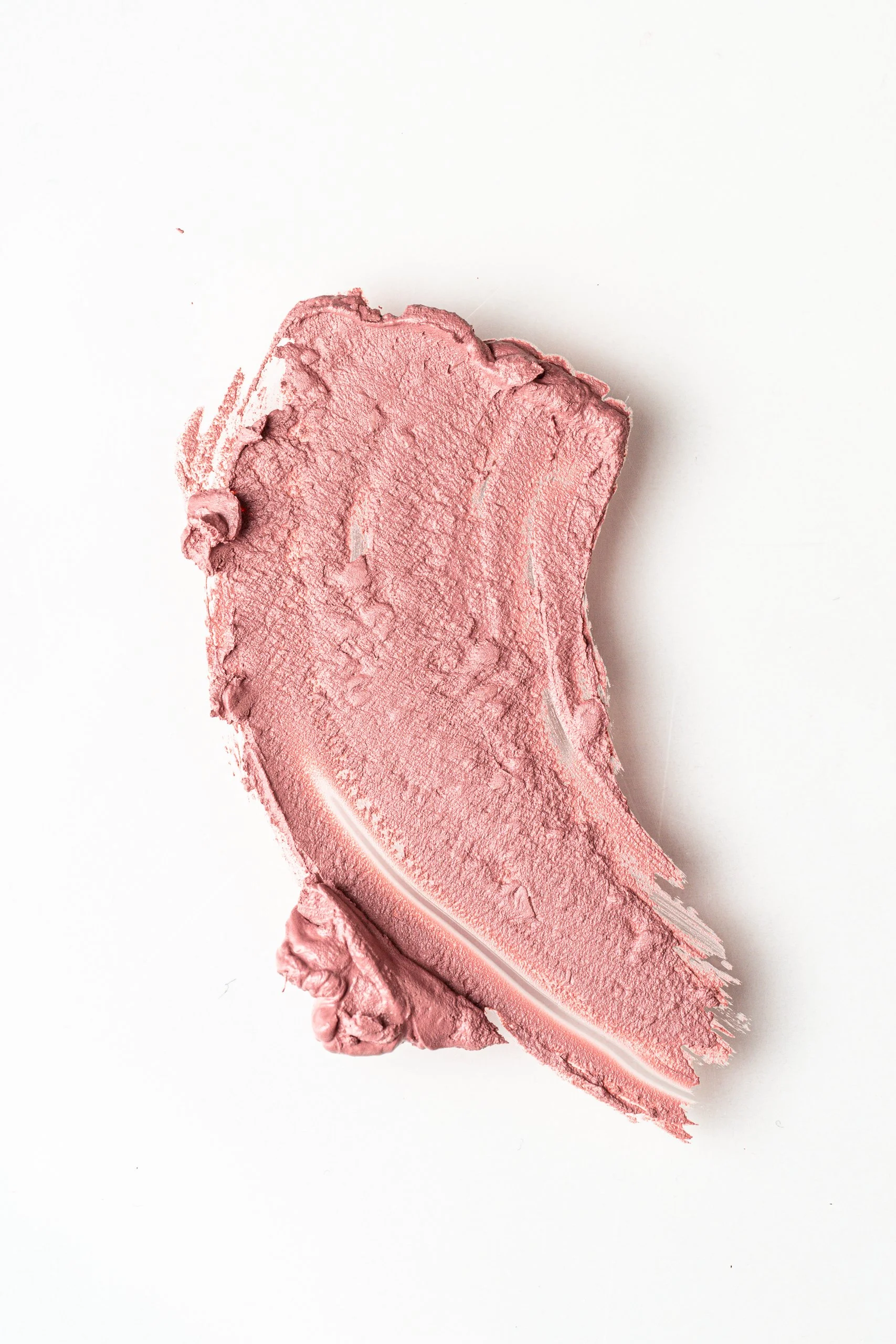 Close-up of a smear of pink lipstick on a white background.