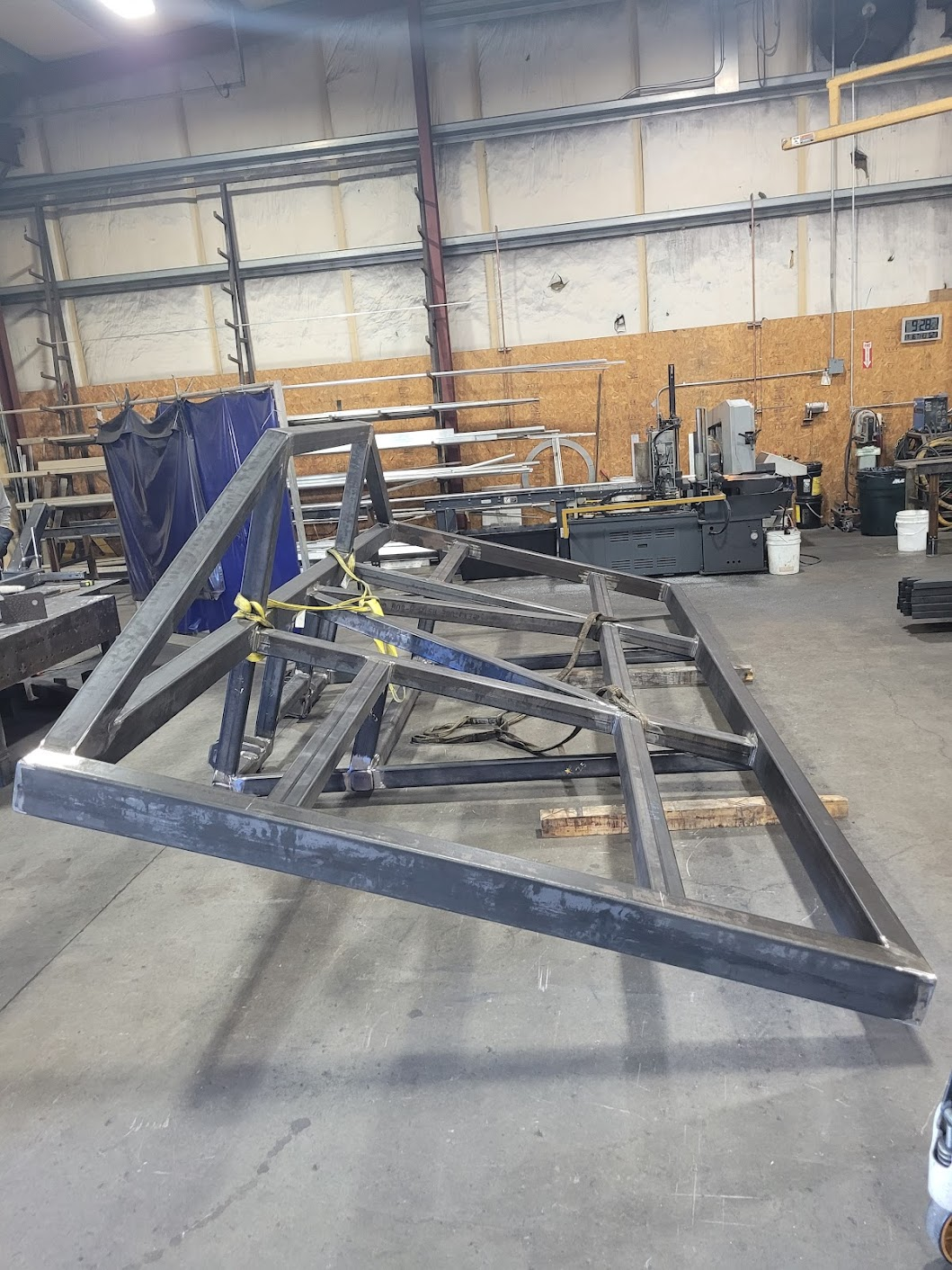 Metal framework structure in a workshop with tools and equipment in the background.