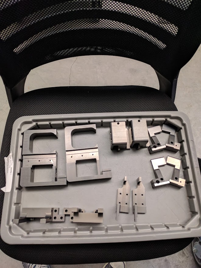 Metal machine parts organized in a plastic storage tray on an office chair.
