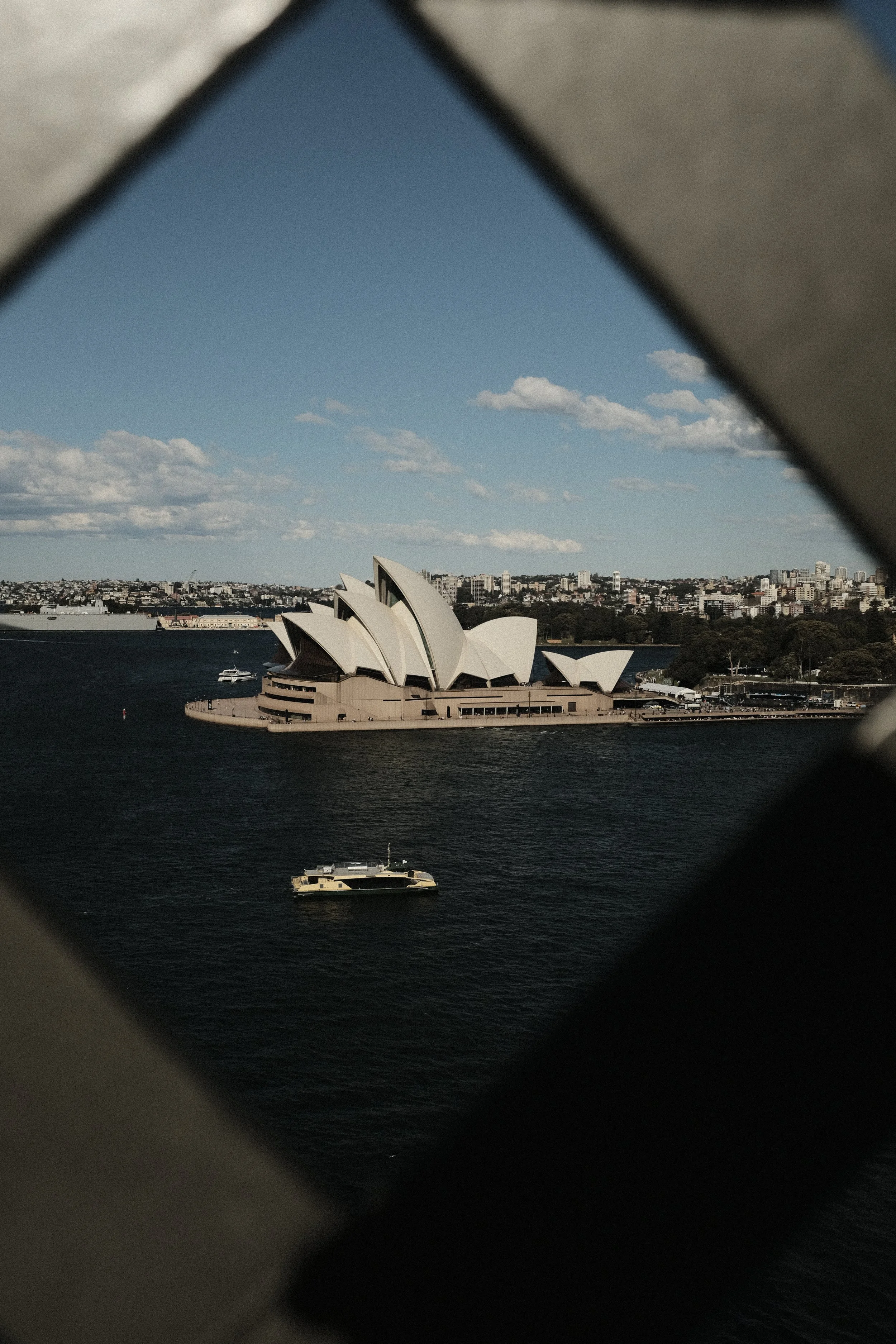 View of the Sydney Opera House and city skyline through a window frame.