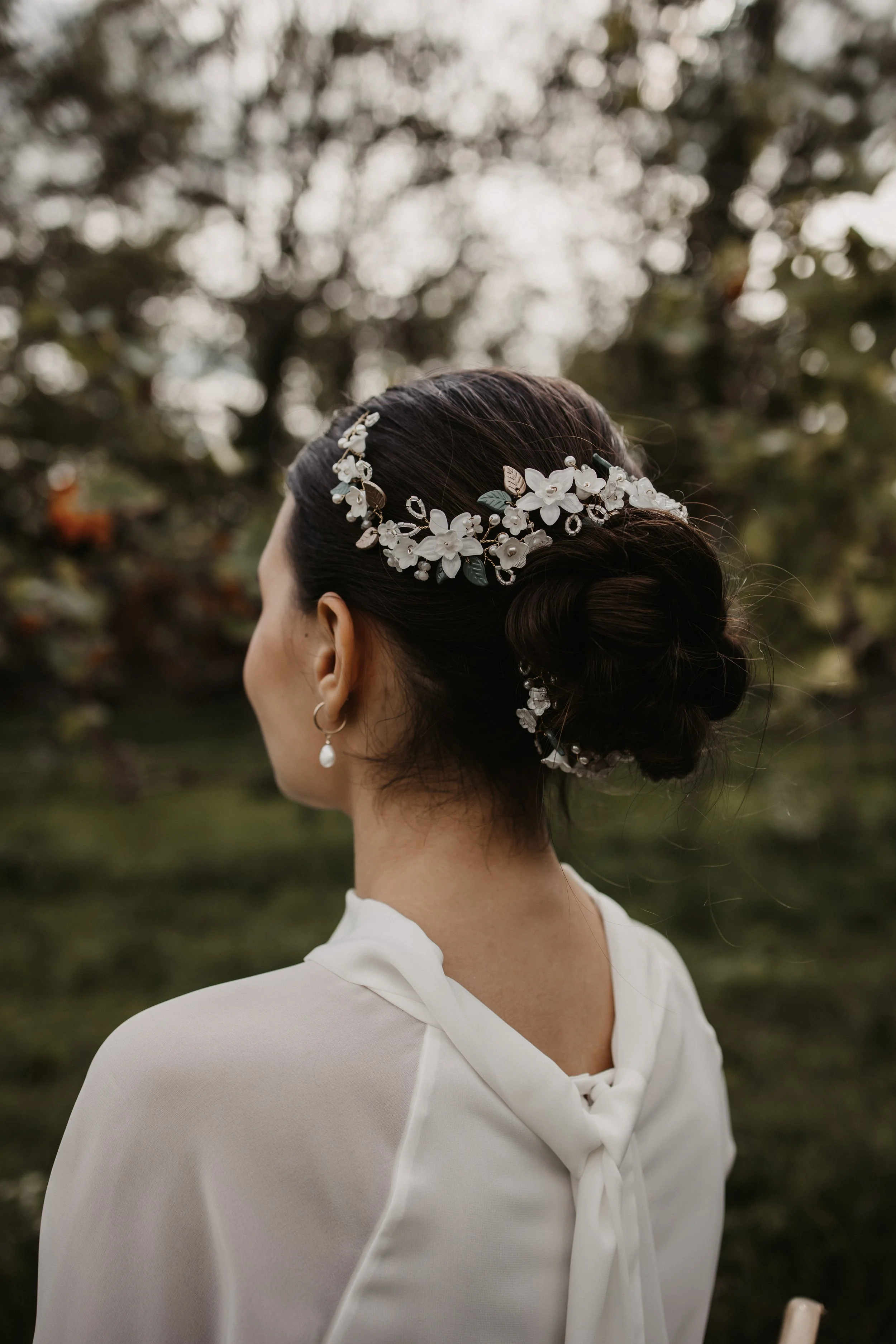 Nahaufnahme eines Mädchens mit aufwändiger Hochsteckfrisur und Blumenschmuck, getragen bei einem Outdoor-Ereignis.