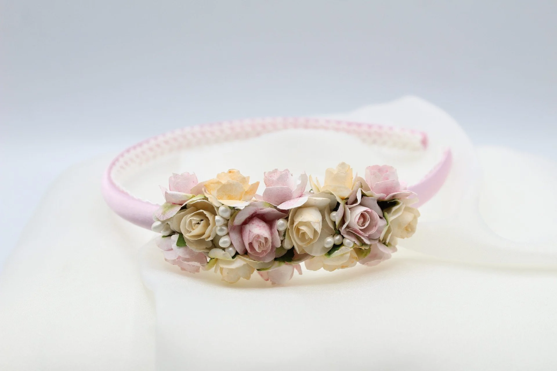 Halsband aus kleinen Rosa und cremefarbenen Rosen mit weißen Perlen auf weißem Stoff