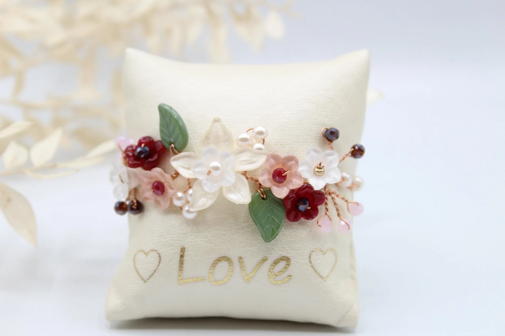Schmuckstück mit Blumenmuster und der Aufschrift 'Love' auf einem Polster