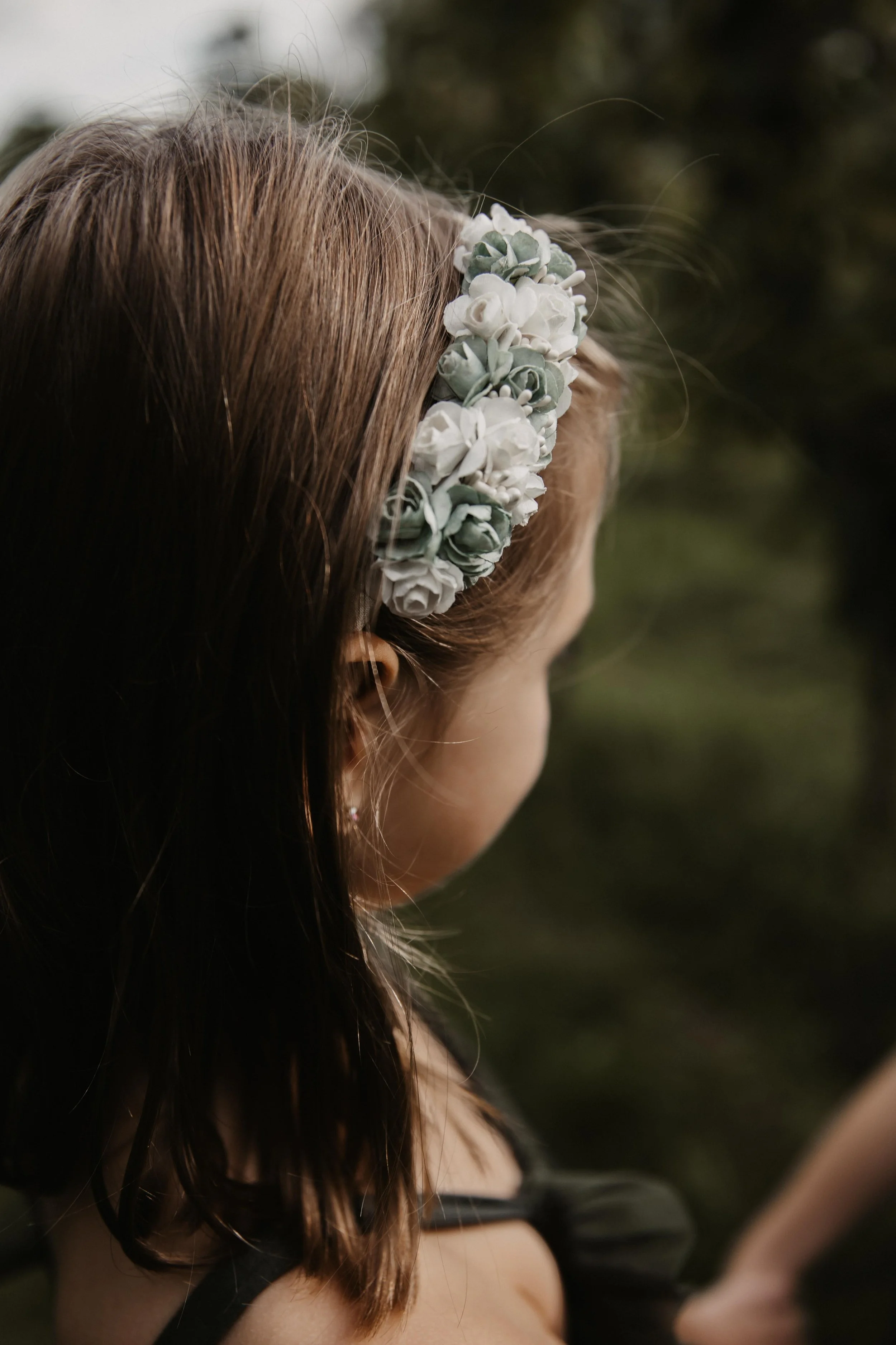 Nahaufnahme eines Mädchens mit braunen Haaren, das eine weiße Blumenkrone trägt.