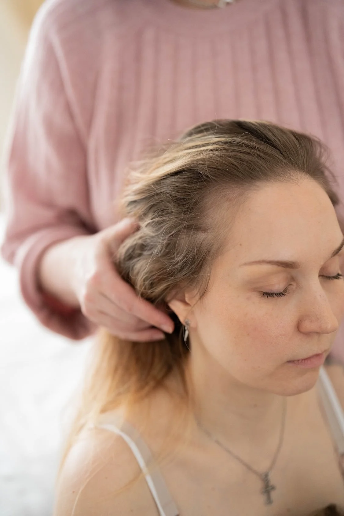 A woman with closed eyes receiving a massage or scalp treatment from another person.