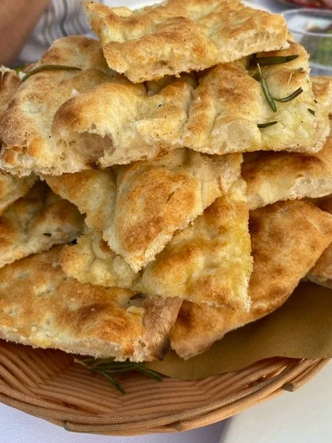 Stack of fried bread or flatbread with herbs in a basket.