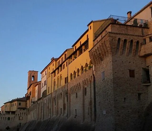 Historic buildings and a bell tower on a hillside, with a blue sky in the background.